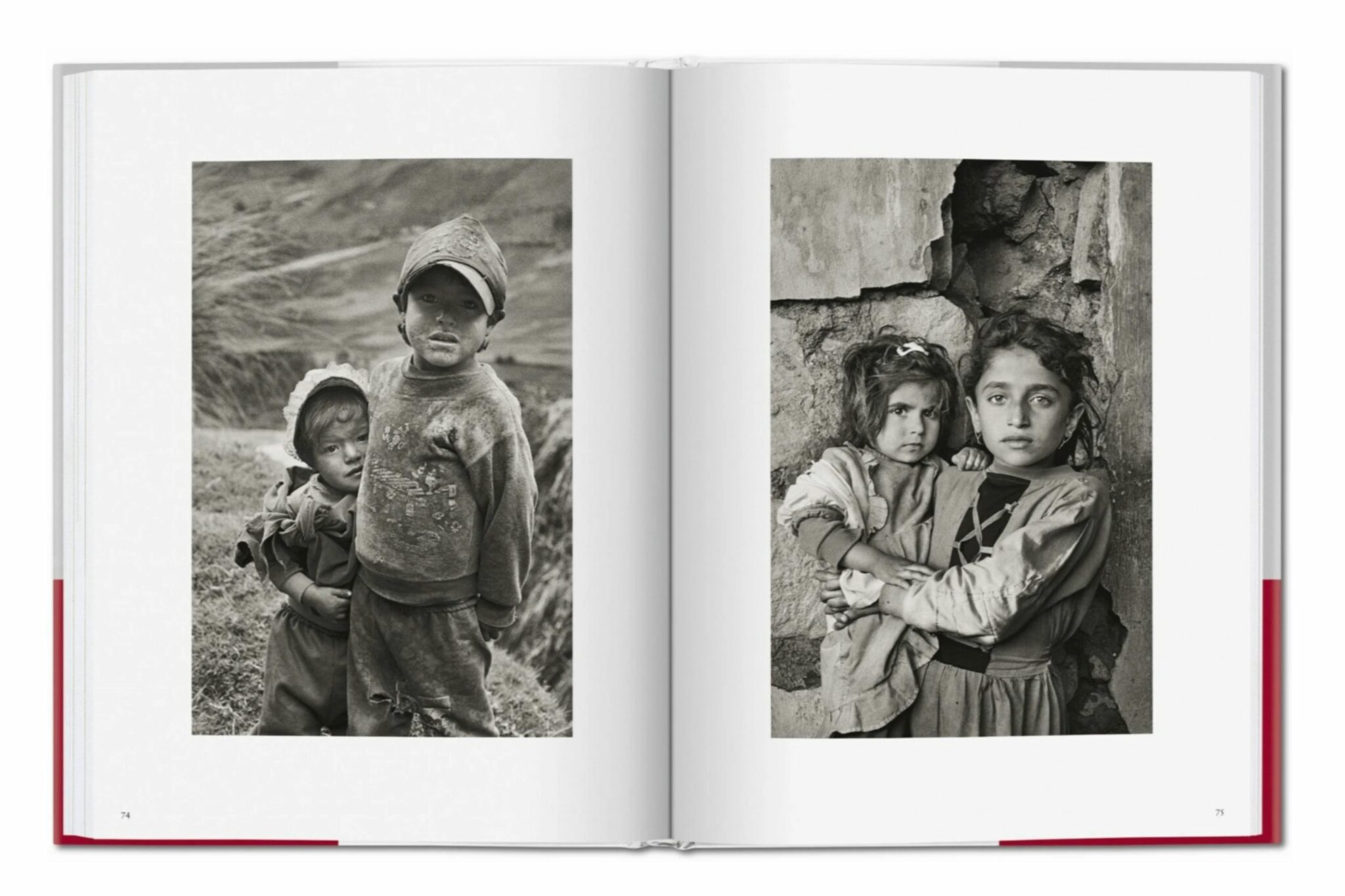 Double-page spread from Sebastião Salgado’s book “Children,” showing two black and white portraits of young African children. The child on the left stands with hands on hips, wearing a striped top and a skirt, while the child on the right sits against a textured wall, smiling slightly, wearing a simple dress with crossed straps.