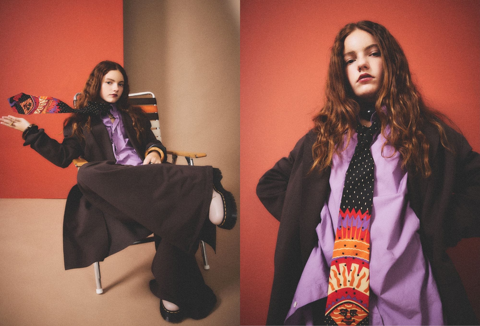 Fashion editorial by Molly Magnuson featuring a young model with long wavy hair, styled in an oversized dark suit with wide-leg trousers, a lavender button-up shirt, and a colorful graphic tie featuring sun and flame motifs. In the left image, the model lounges confidently in a folding chair, with one hand flipping the tie for dramatic flair. In the right image, the model stands with hands on hips against a burnt orange backdrop, exuding boldness and attitude. The look is completed with chunky white platform shoes, blending playful rebellion with tailored sophistication.
