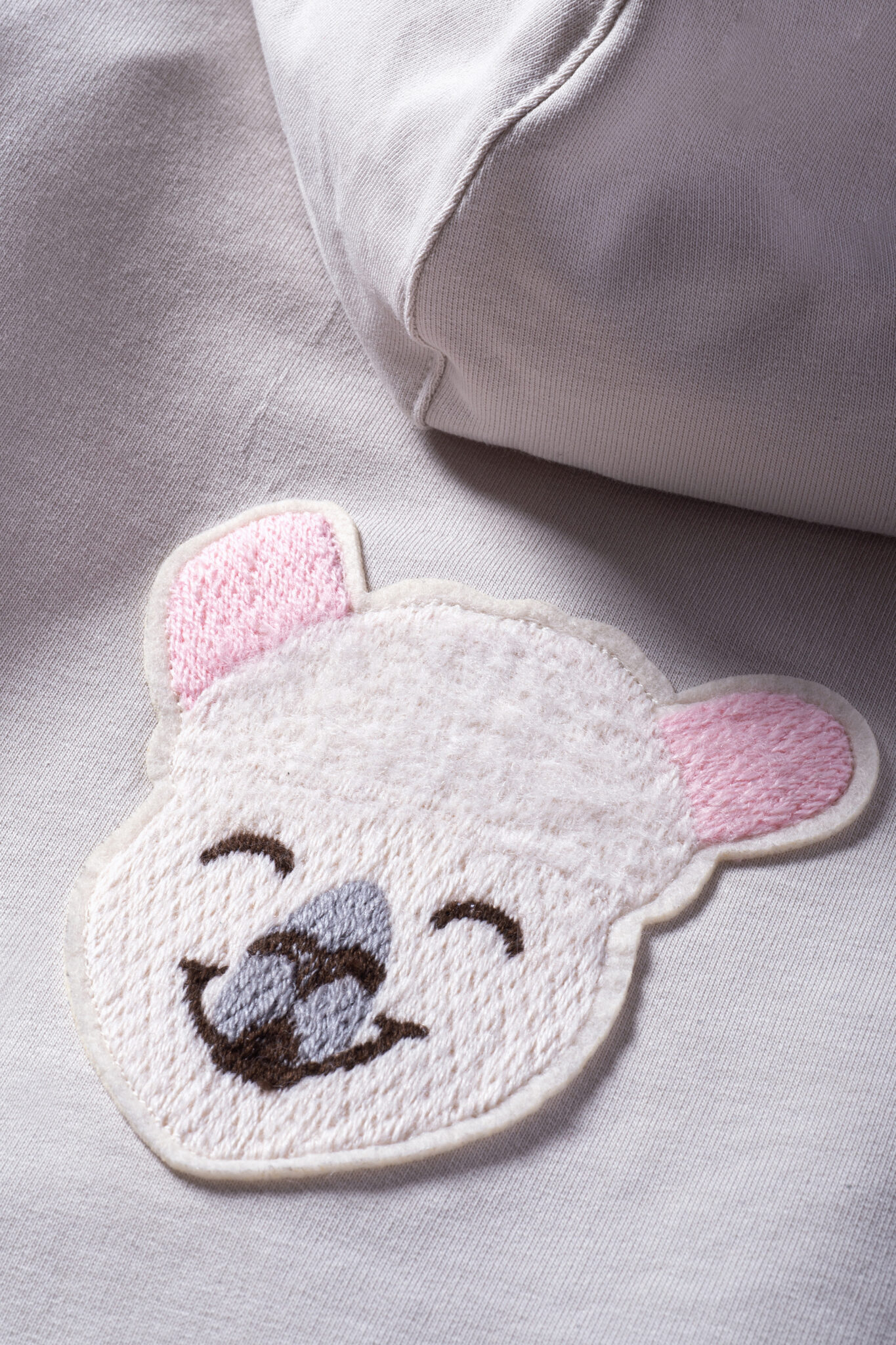 Close-up of pink bear embroidery detail on knitwear from Gensami FW25.