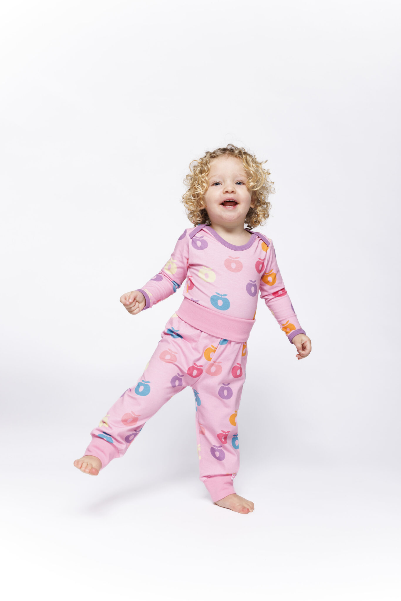 Småfolk F/W25 – toddler in pink pajama with multicolor apple print, fall winter 2025 kidswear.