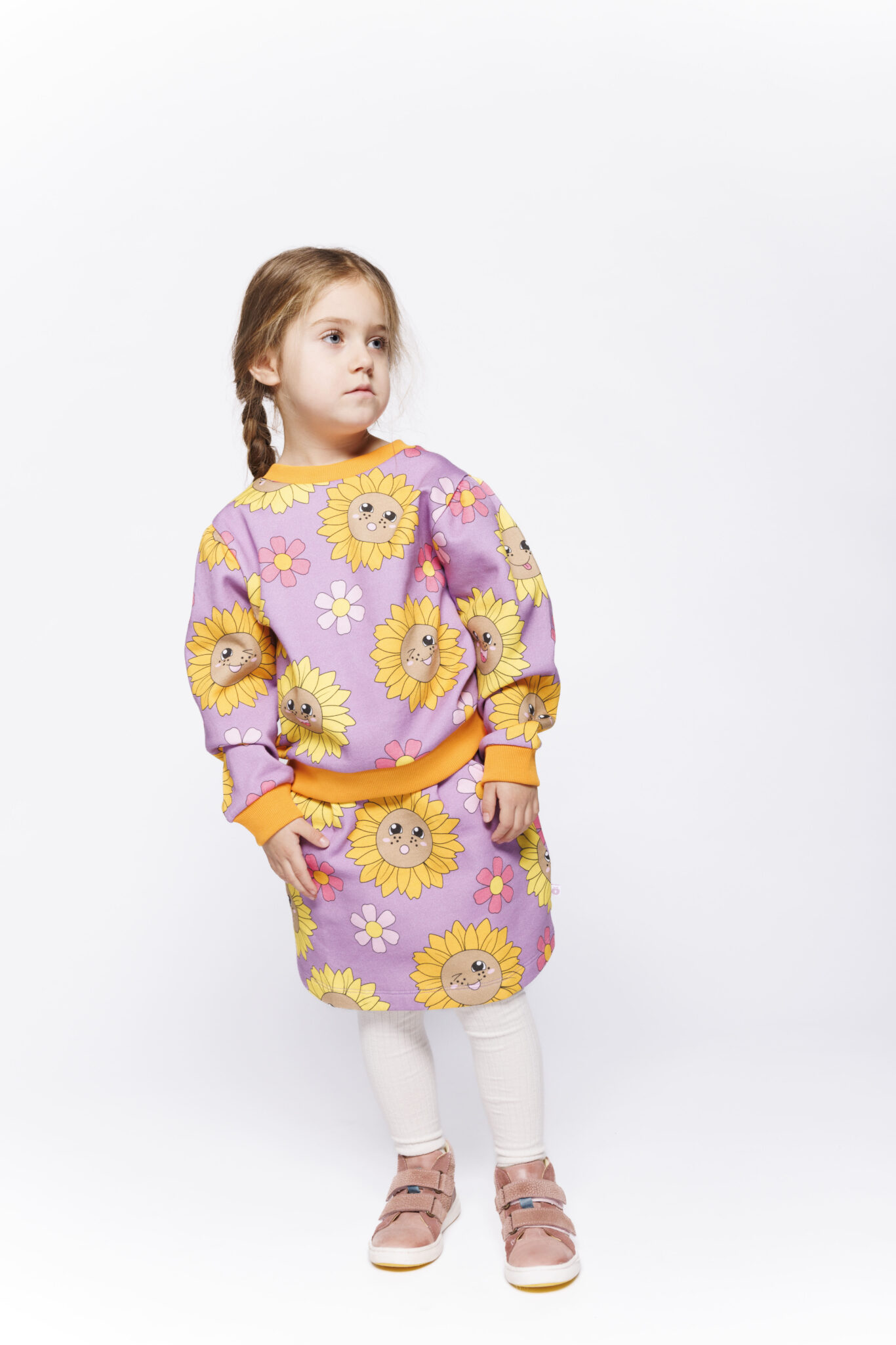 Småfolk F/W25 – girl in lilac sweatshirt and skirt with sunflower print, fall winter 2025 kidswear.
