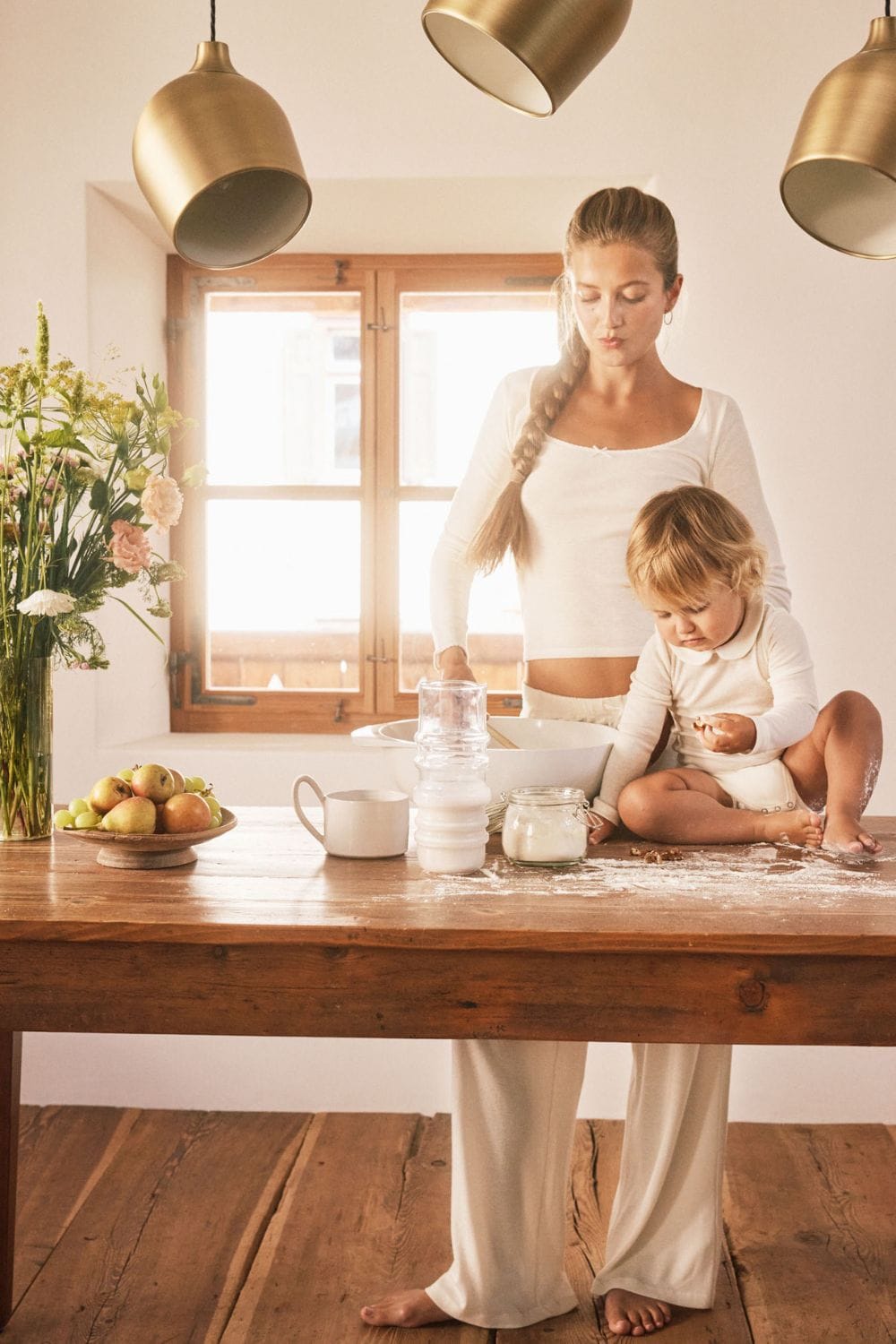 Mother and child in matching cream loungewear from the Minimalisma x Zoë Pastelle capsule collection Fall/Winter 25, cooking together at home, featured on Scimparello Magazine.