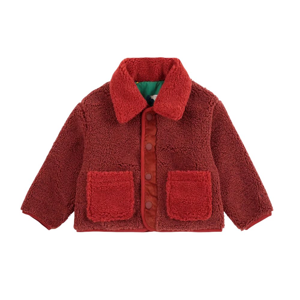 Red teddy jacket by BOBO CHOSES, featured on Scimparello Magazine. Soft, cozy, and playful with patch pockets and contrast details — a warm FW25 kidswear essential.