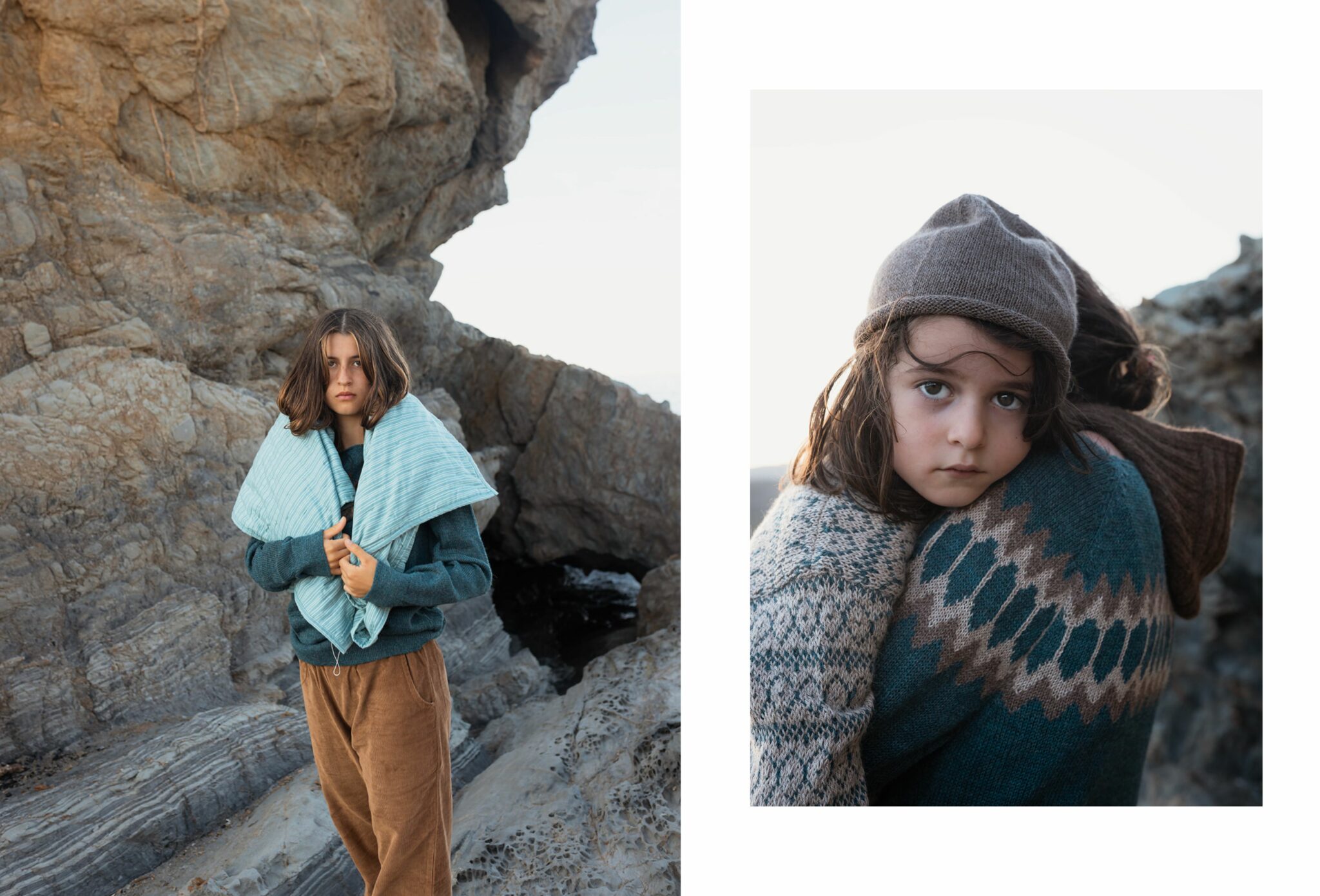 Two children on coastal rocks wearing knitwear and earthy-toned outfits; one stands wrapped in a light blue quilted scarf, while the other is carried, looking toward the camera. Photo by Manuela Franjou for Scimparello Magazine.
