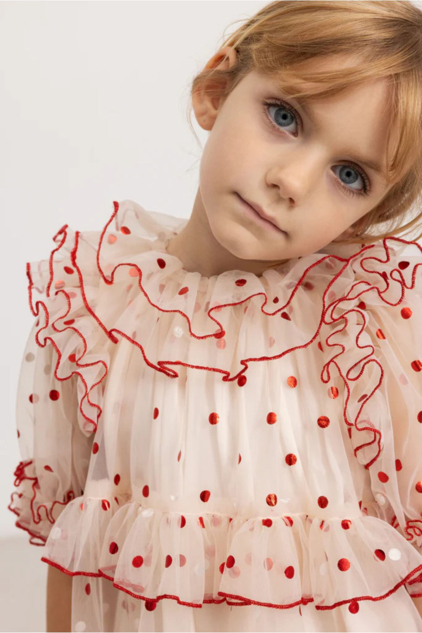 MarMar Copenhagen SS26 girls collection featured in Scimparello Magazine – close-up portrait of a girl wearing a cream sheer dress with red polka dots and ruffled neckline, soft neutral background.