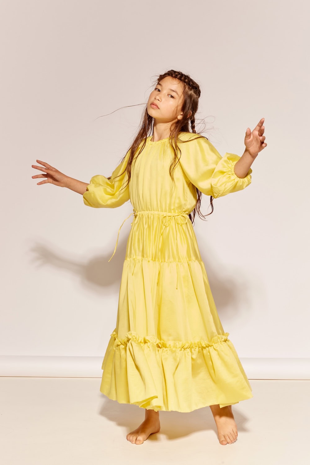 The Middle Daughter SS26 bright yellow tiered maxi dress with long sleeves and soft ruffle details on young girl. Scimparello Magazine.