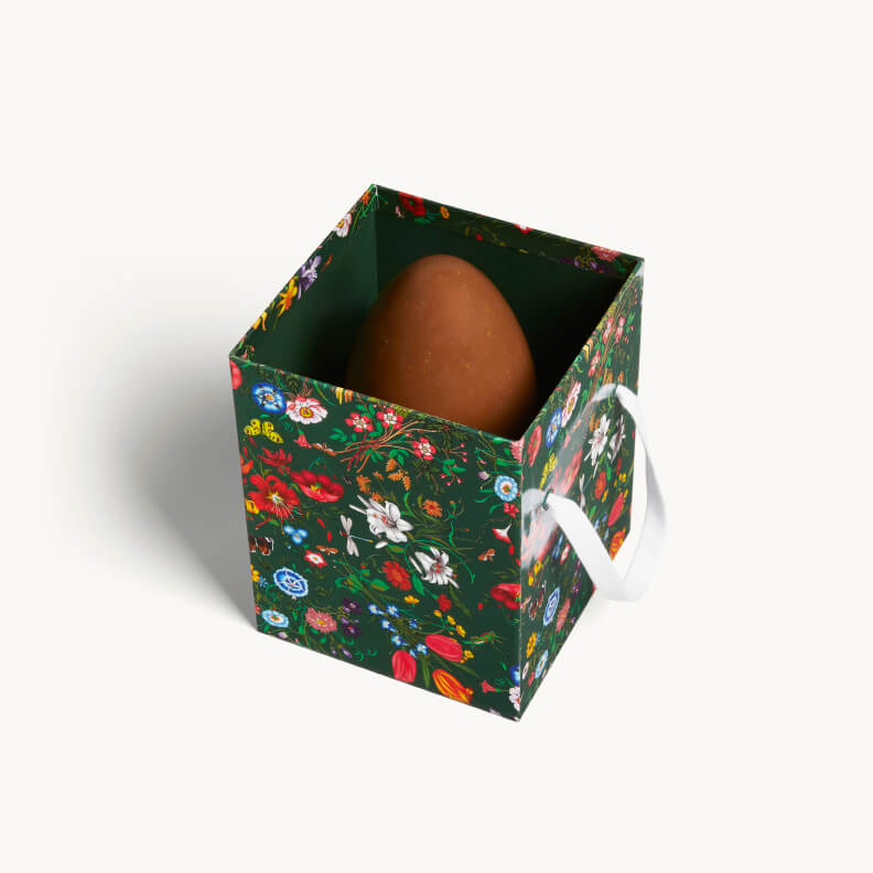 Assorted Gucci Osteria mini chocolate eggs in multiple flavors displayed inside a Gucci Flora decorated gift box