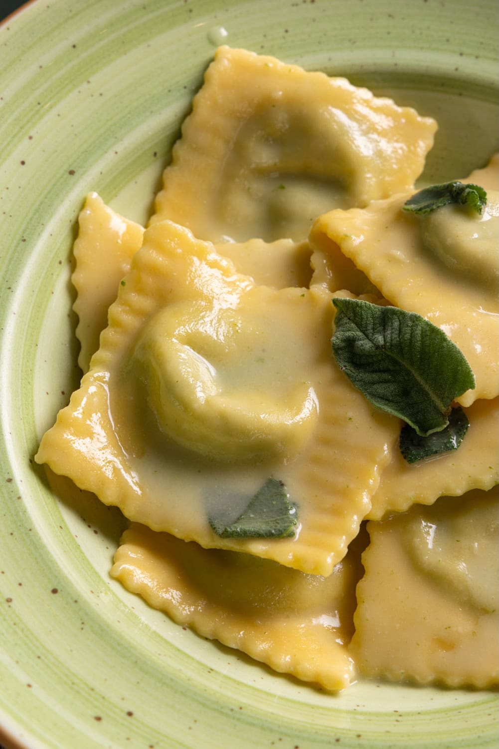 ravioli dish with butter cream and sage served on a pale green plate