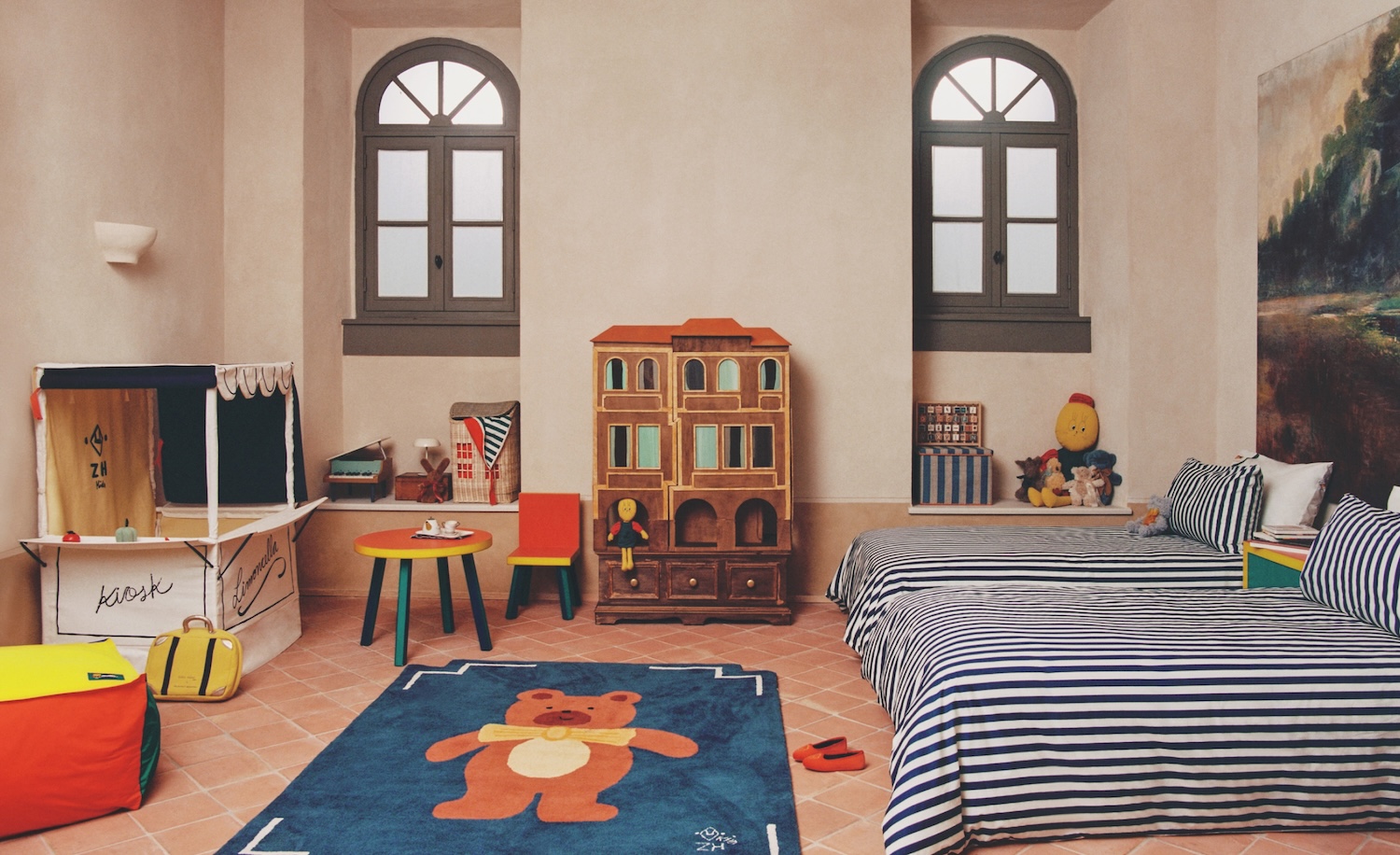Camera per bambini Zara Home x The Animals Observatory con letti a righe, tappeto con orsetto illustrato, giochi vintage e arredi colorati dal mood rétro e creativo.