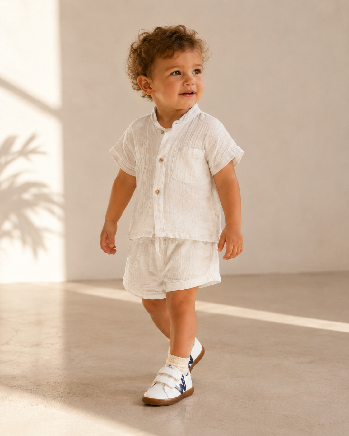 Toddler wearing a crisp white summer outfit with white and navy Walkey barefoot shoes in warm natural light, Scimparello Magazine.