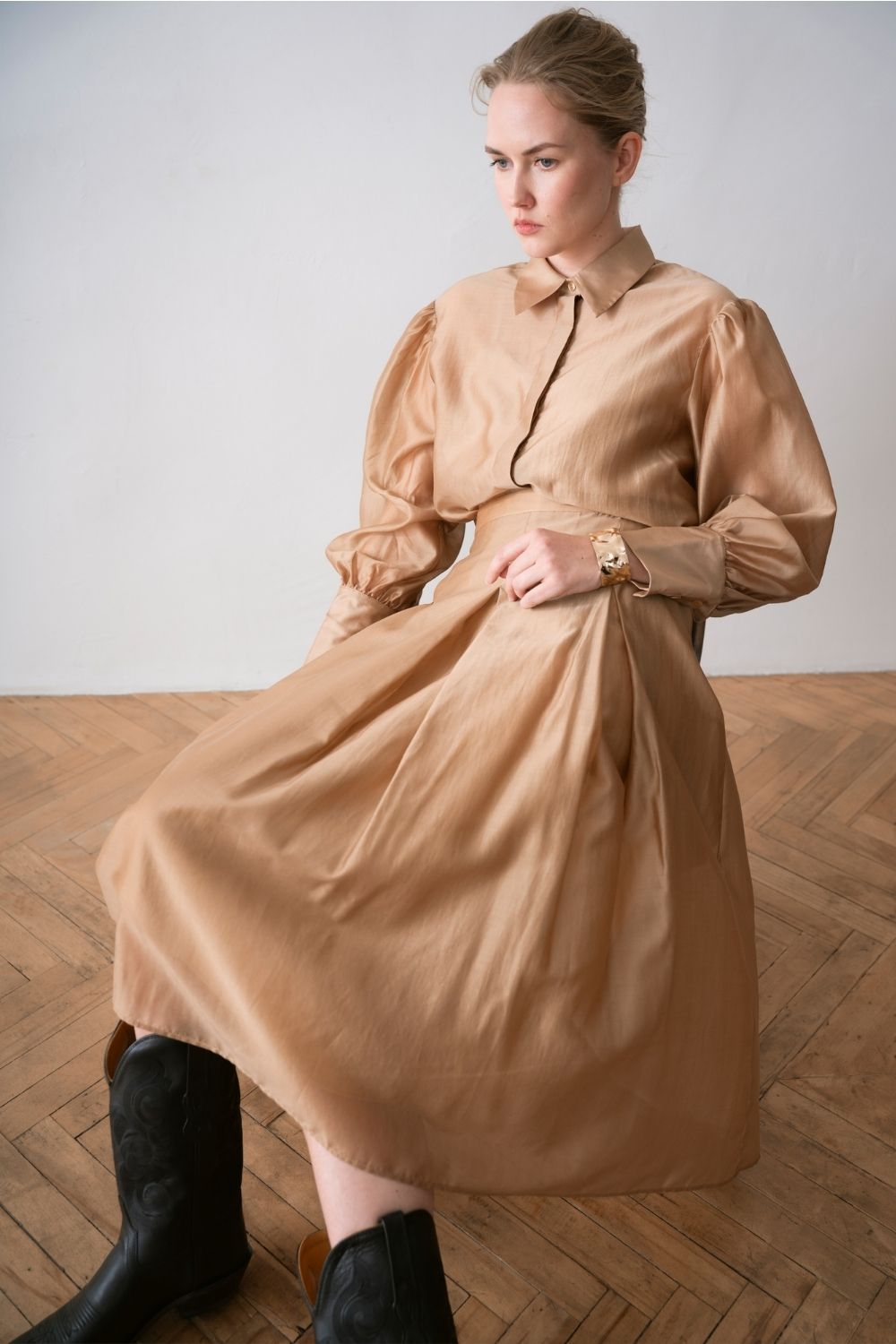 Paade Mode women collection look featuring a camel shirt dress with voluminous sleeves, styled with black boots and a gold bracelet, featured on Scimparello Magazine.