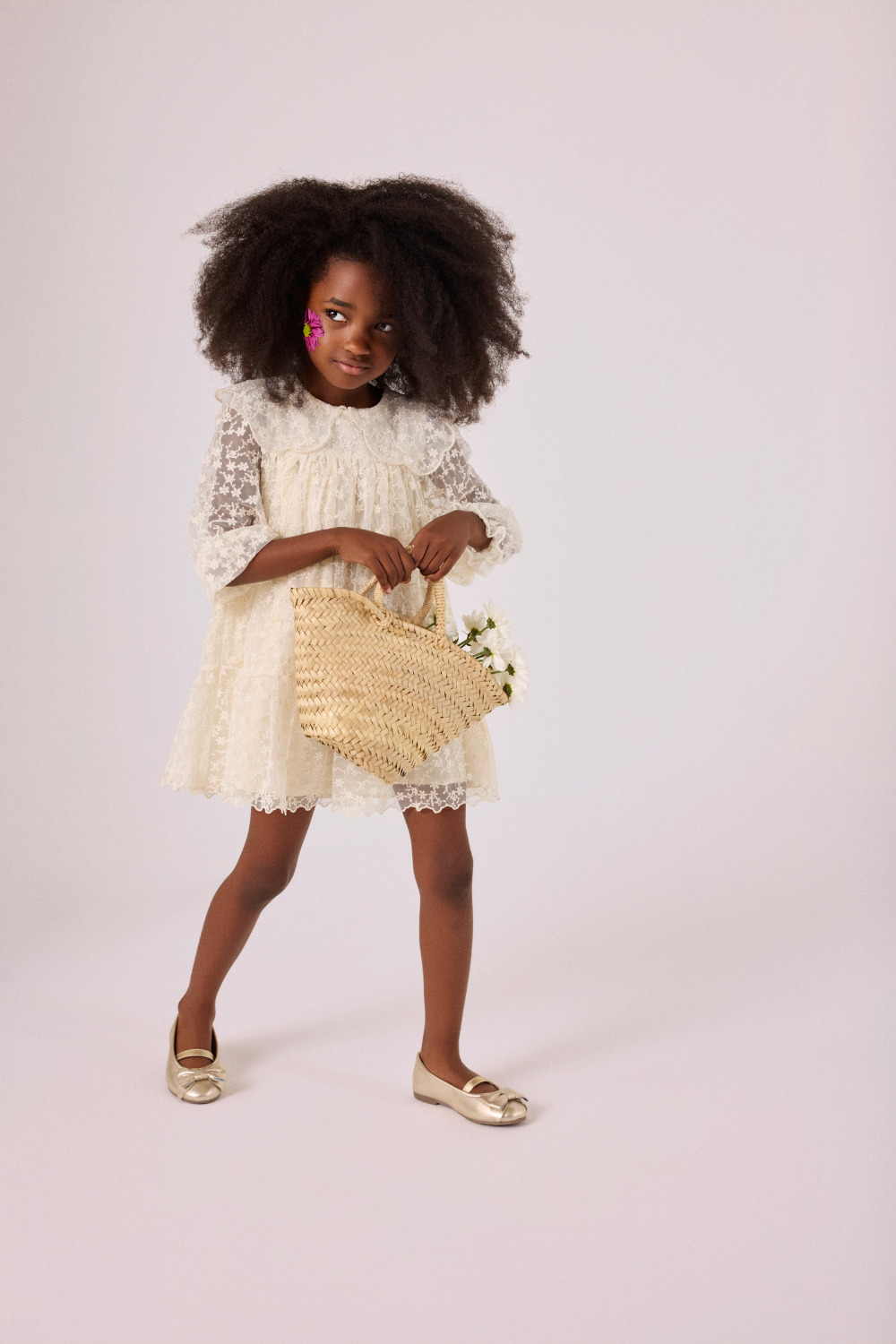 Girl in a cream lace dress and gold Gioseppo Kids SS26 ballet flats, holding a woven basket with flowers for Scimparello Magazine.