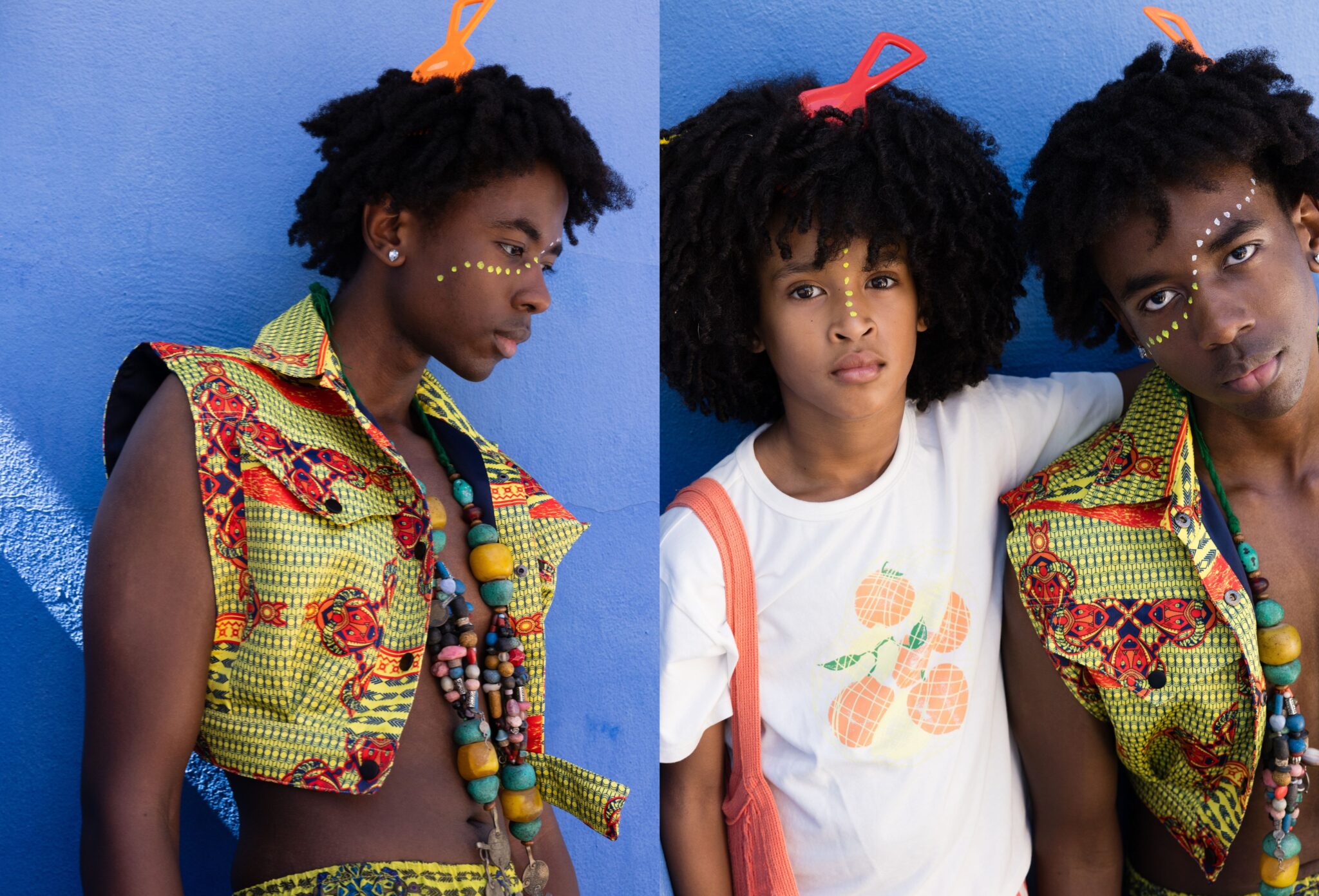 Two young models with natural textured hair and face paint details posed against a vivid blue wall, wearing bold patterned garments and layered accessories, expressive portraits with strong color contrast, kids fashion editorial Culture Clash by Hannah Mentz shot in South Africa for Scimparello Magazine