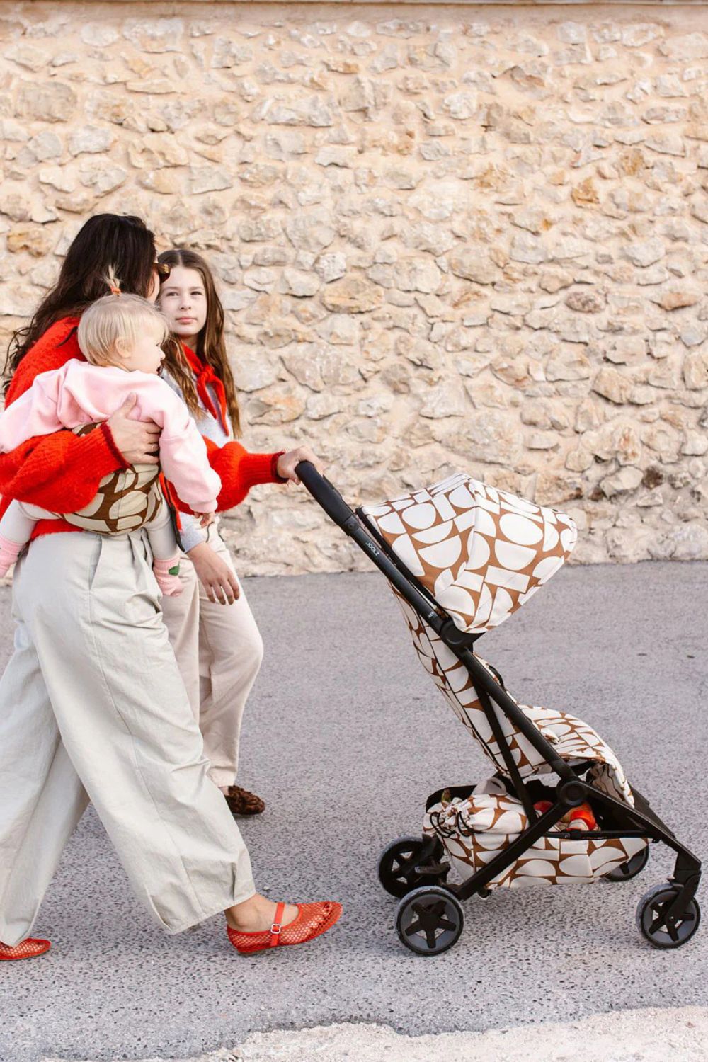 Parent walking with the Joolz Aer² stroller in boho print while carrying a child in the Wildride Toddler Carrier, Scimparello Magazine