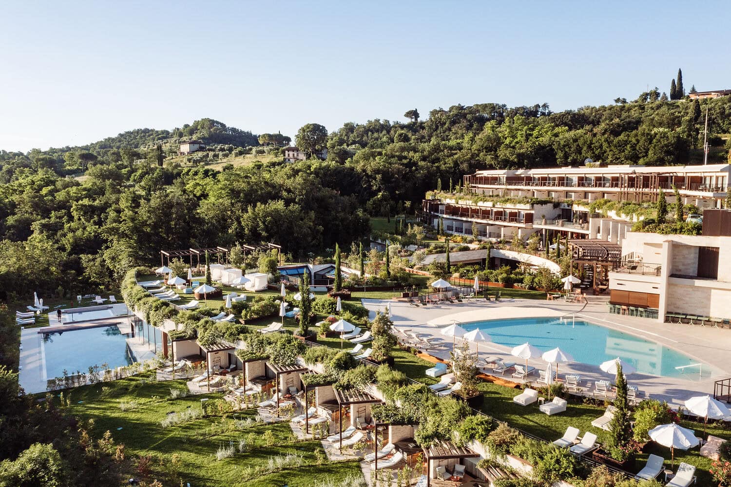 Aerial view of A-ROSA Lago di Garda resort in Salò, surrounded by lush gardens, panoramic pools and terraces overlooking the lake.