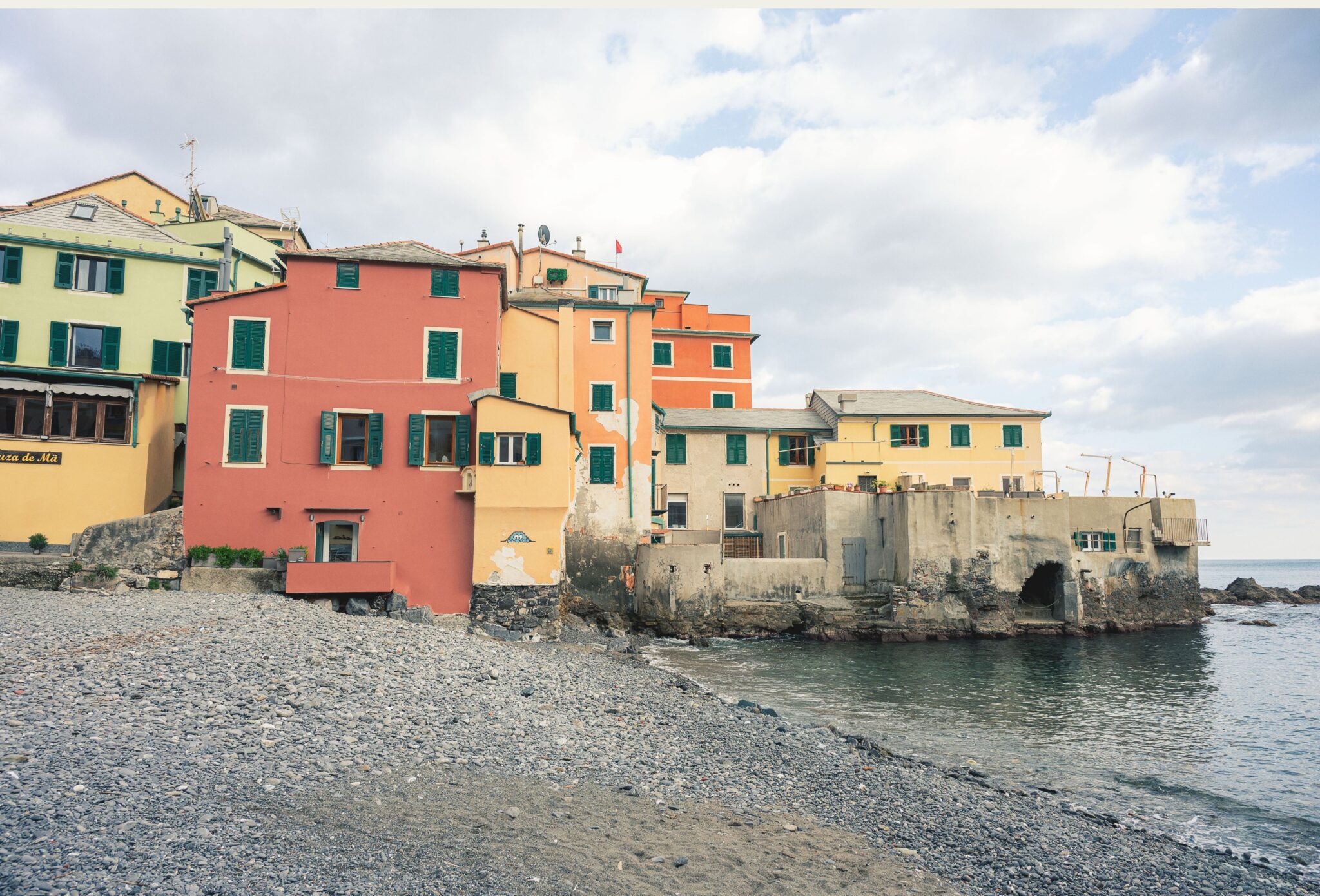 Pastel seaside houses and pebble beach in Boccadasse, Liguria, photographed by Ilaria & Silvia Cianciaruso for Scimparello Magazine.