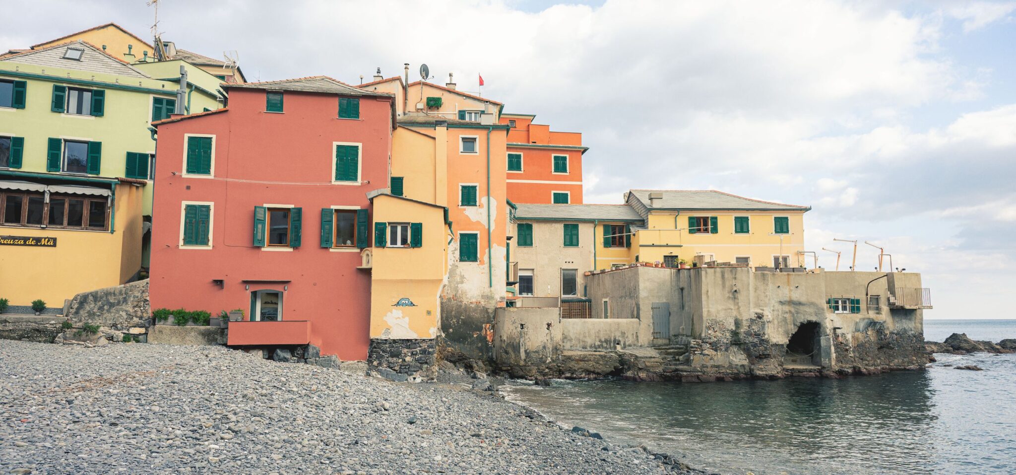 Pastel seaside houses and pebble beach in Boccadasse, Liguria, photographed by Ilaria & Silvia Cianciaruso for Scimparello Magazine.