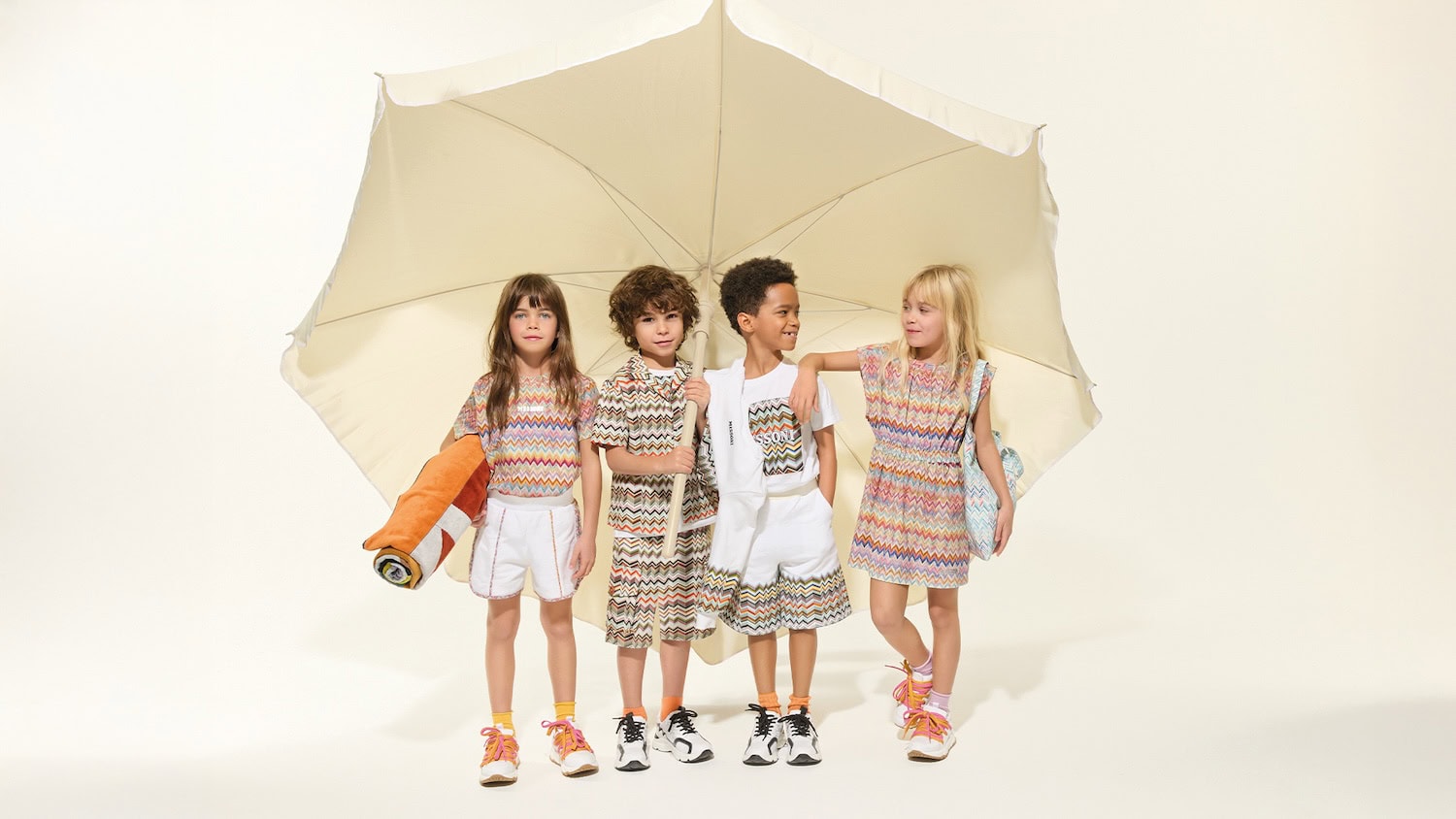 Group of children wearing Missoni Kids SS26 summer outfits featuring iconic multicolour zigzag prints, coordinated separates and lightweight dresses inspired by beach holidays.