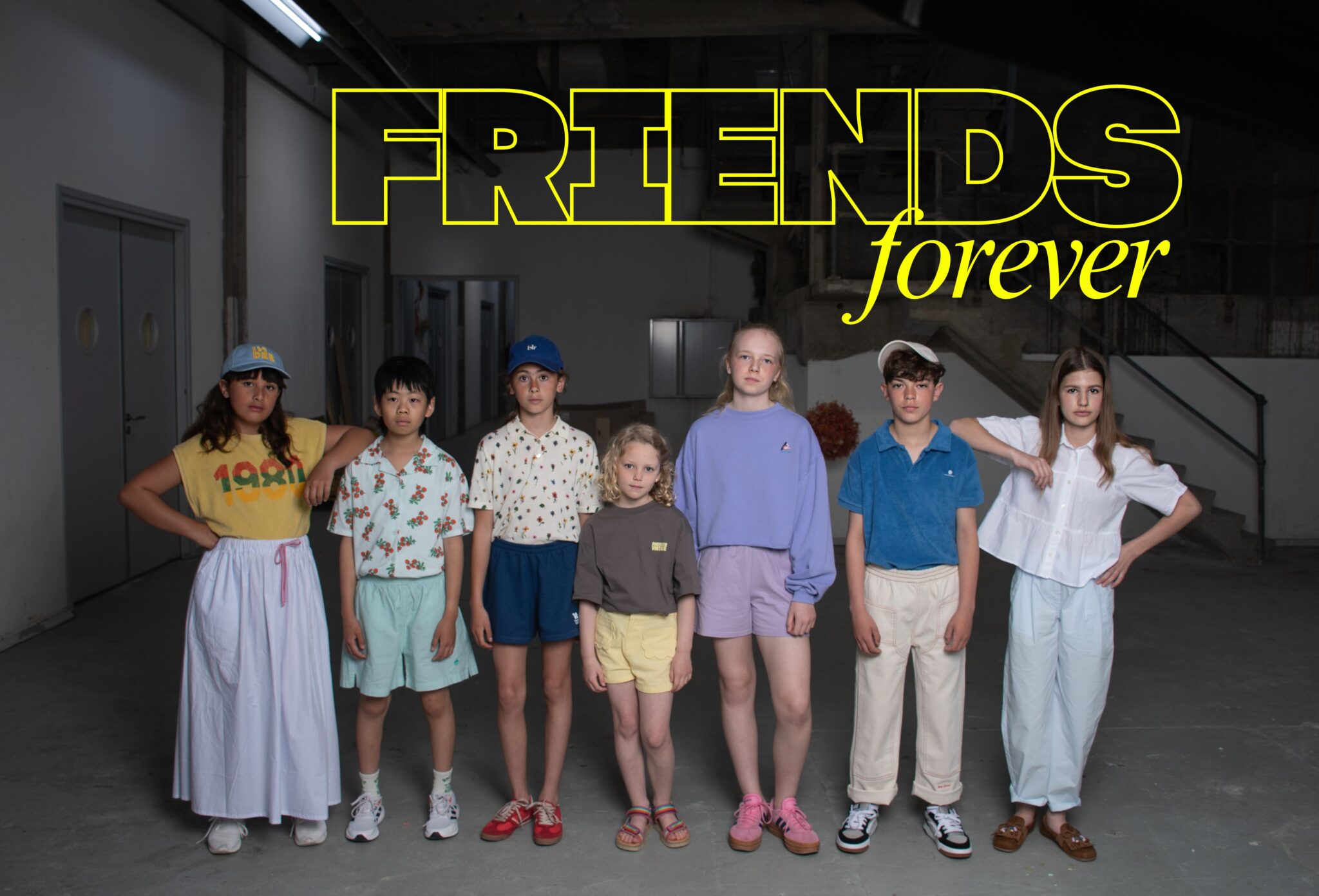 Group of children posing together in casual summer looks inside an industrial space for the kids fashion editorial Friends Forever, Scimparello Magazine.