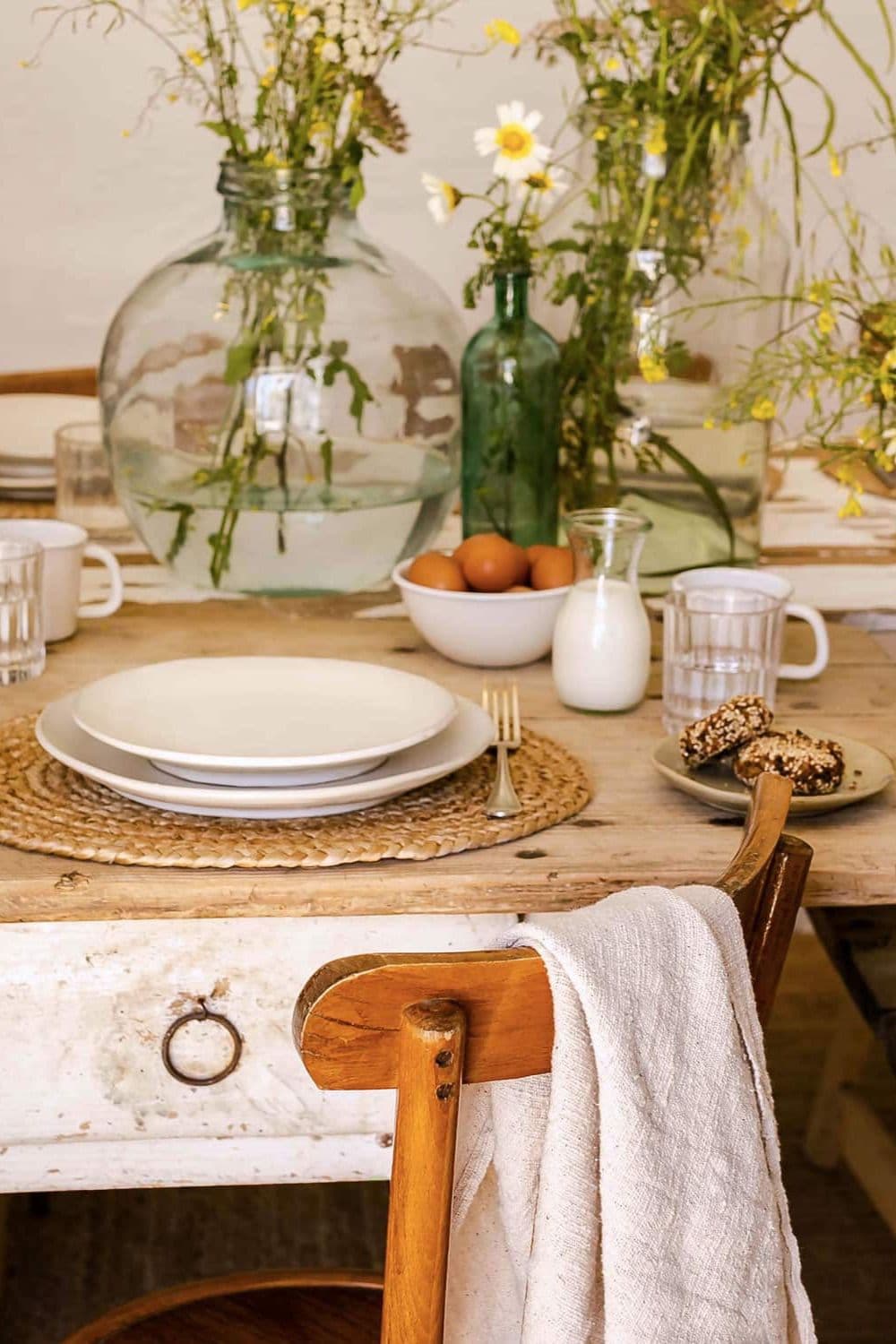 Rustic dining table styled with handcrafted ceramic plates by N°74, wildflowers in glass vases, natural textiles and artisanal tableware.