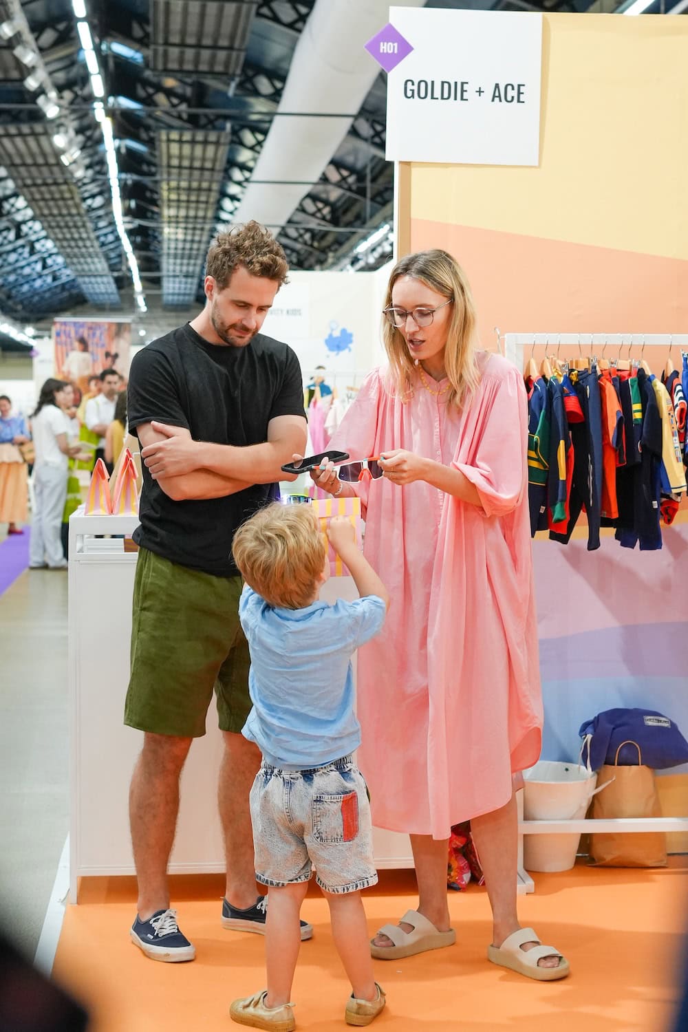 Visitors discover new childrenswear collections at Playtime Paris, where a family interacts with exhibitors showcasing colorful Spring/Summer designs and emerging kids' fashion brands.