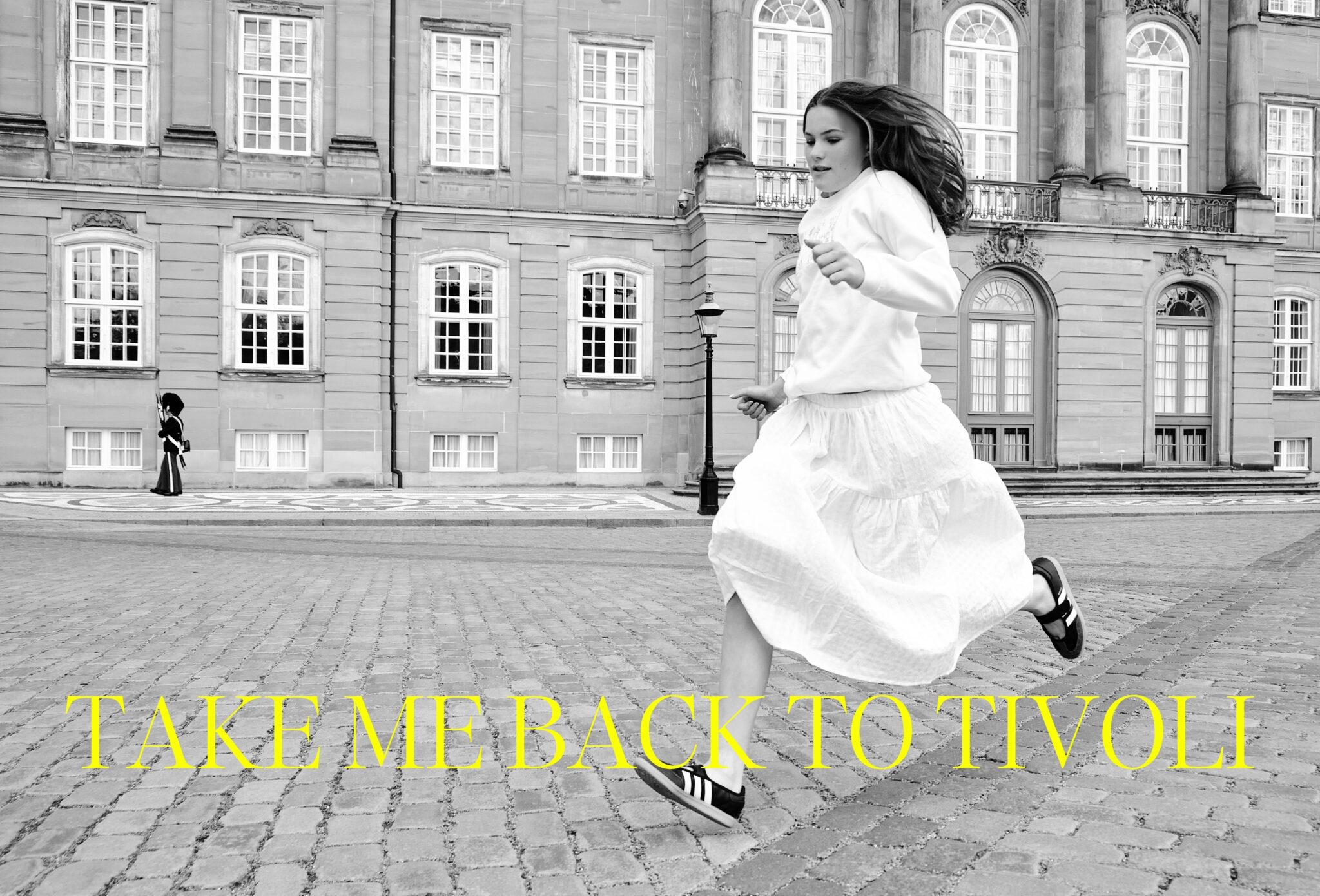 Black and white teen fashion editorial Take Me Back to Tivoli photographed by Erica Allen in Copenhagen, featuring a girl running in a white skirt in front of a historic building for Scimparello Magazine.