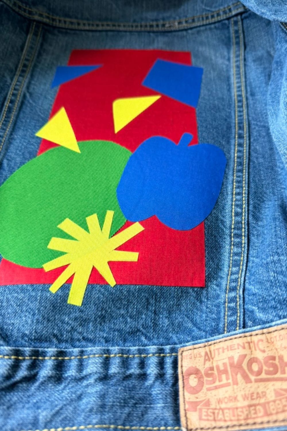Denim jacket transformed with colourful apple and graphic patches for RE.Twist by Anne-Charlotte Le Grand, showing playful upcycling for pre-loved childrenswear on Scimparello Magazine.