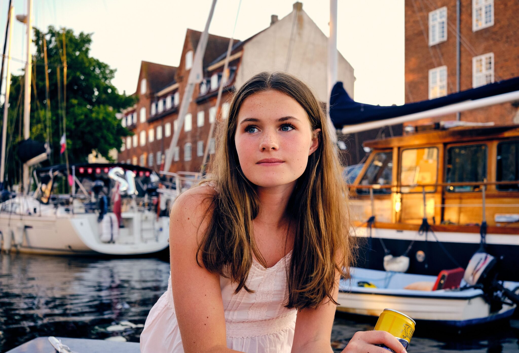 Teen fashion editorial Take Me Back to Tivoli photographed by Erica Allen in Copenhagen, featuring a girl in a white summer dress by the harbour at golden hour for Scimparello Magazine.