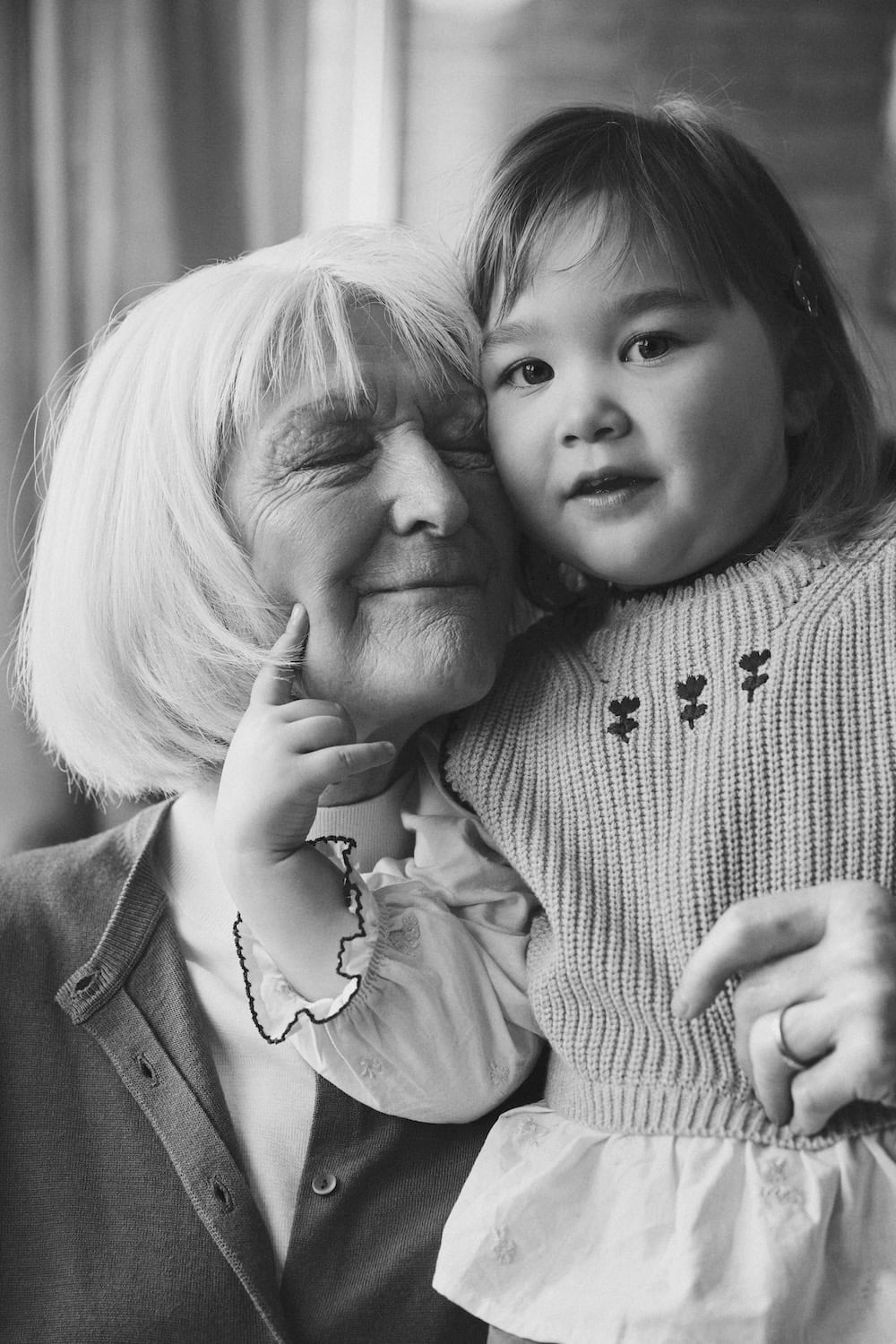 Black and white portrait of a grandmother hugging her granddaughter, celebrating the intergenerational bond behind Bundgaard's Generations campaign.