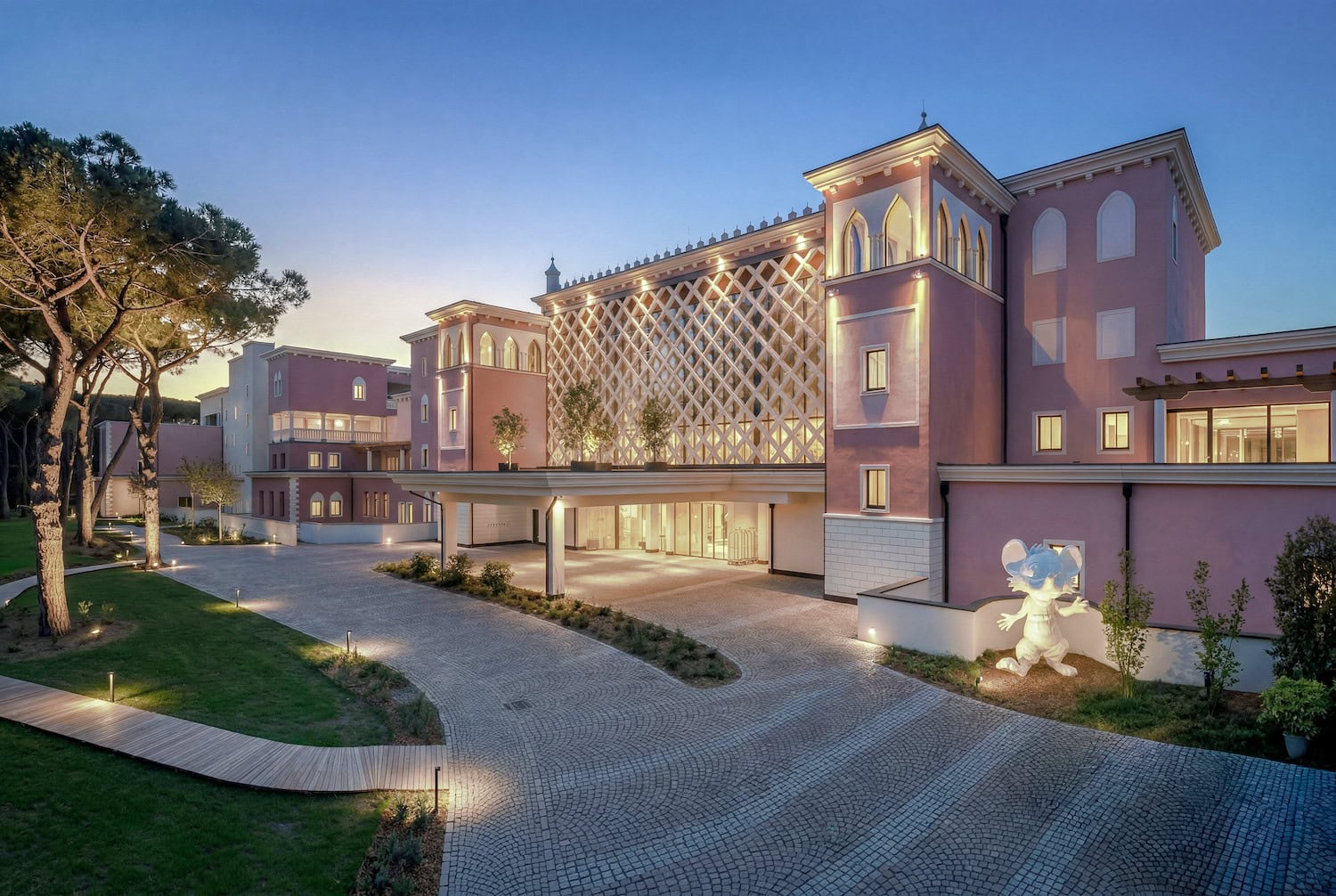 Exterior of Cavallino Bianco Caorle – Venezia Luxury Family Beach Resort at sunset, surrounded by pine trees and designed for luxury family holidays on the Adriatic coast.