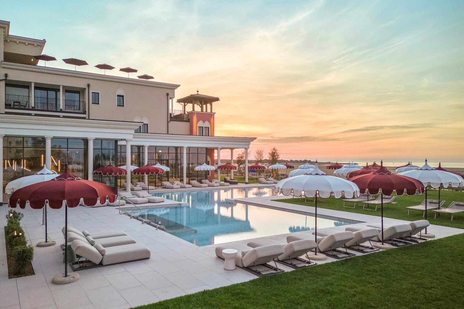 Outdoor swimming pool at Cavallino Bianco Caorle – Venezia Luxury Family Beach Resort, featuring elegant sun loungers and parasols overlooking the Adriatic Sea.