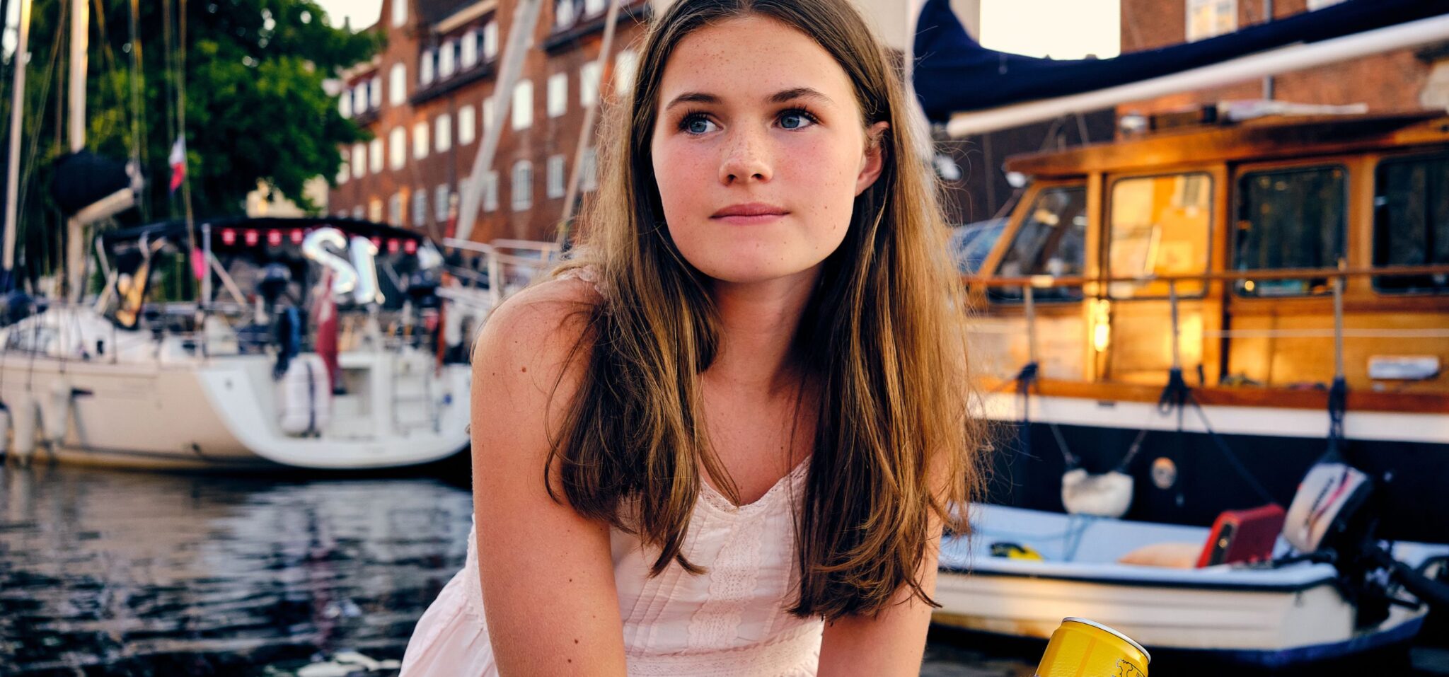 Teen fashion editorial Take Me Back to Tivoli photographed by Erica Allen in Copenhagen, featuring a girl in a white summer dress by the harbour at golden hour for Scimparello Magazine.