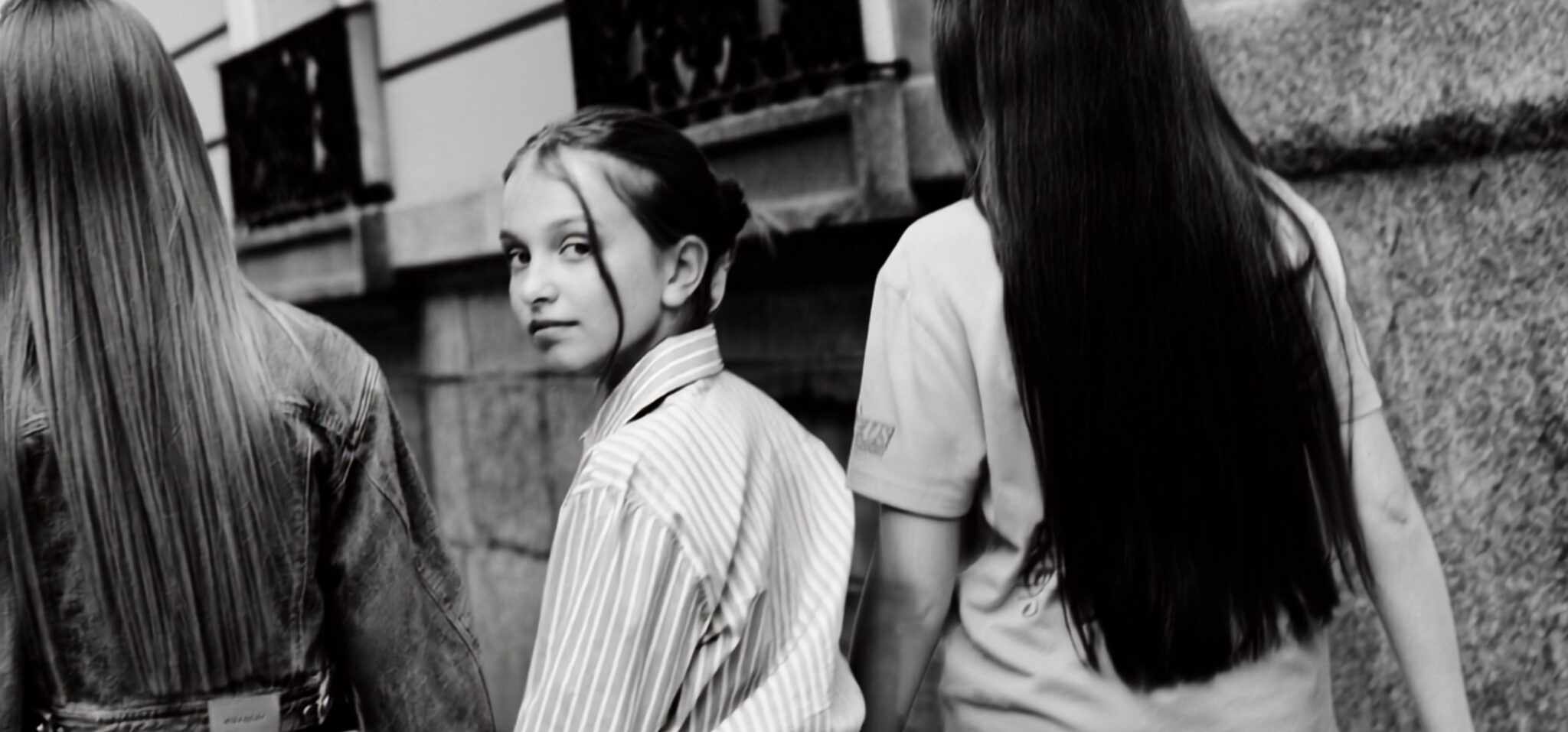 Black and white teen fashion editorial City Belongs to Us photographed by Sandra Martinez and Mara Rodriguez, featuring three girls sitting outside a café in an urban street scene for Scimparello Magazine.