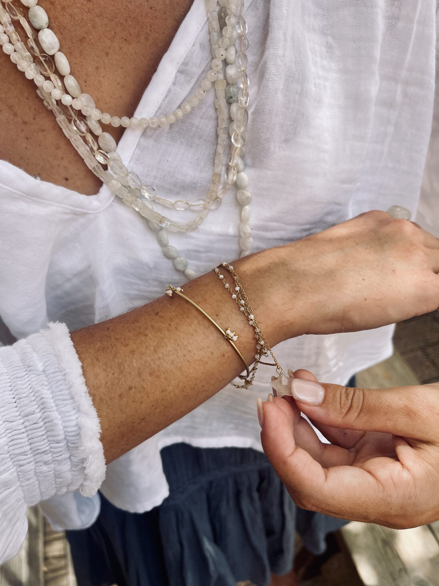 N°74 jewelry handmade in India, featuring layered natural stone necklaces, delicate bracelets and a small pink stone charm worn with a white blouse for Scimparello Magazine.