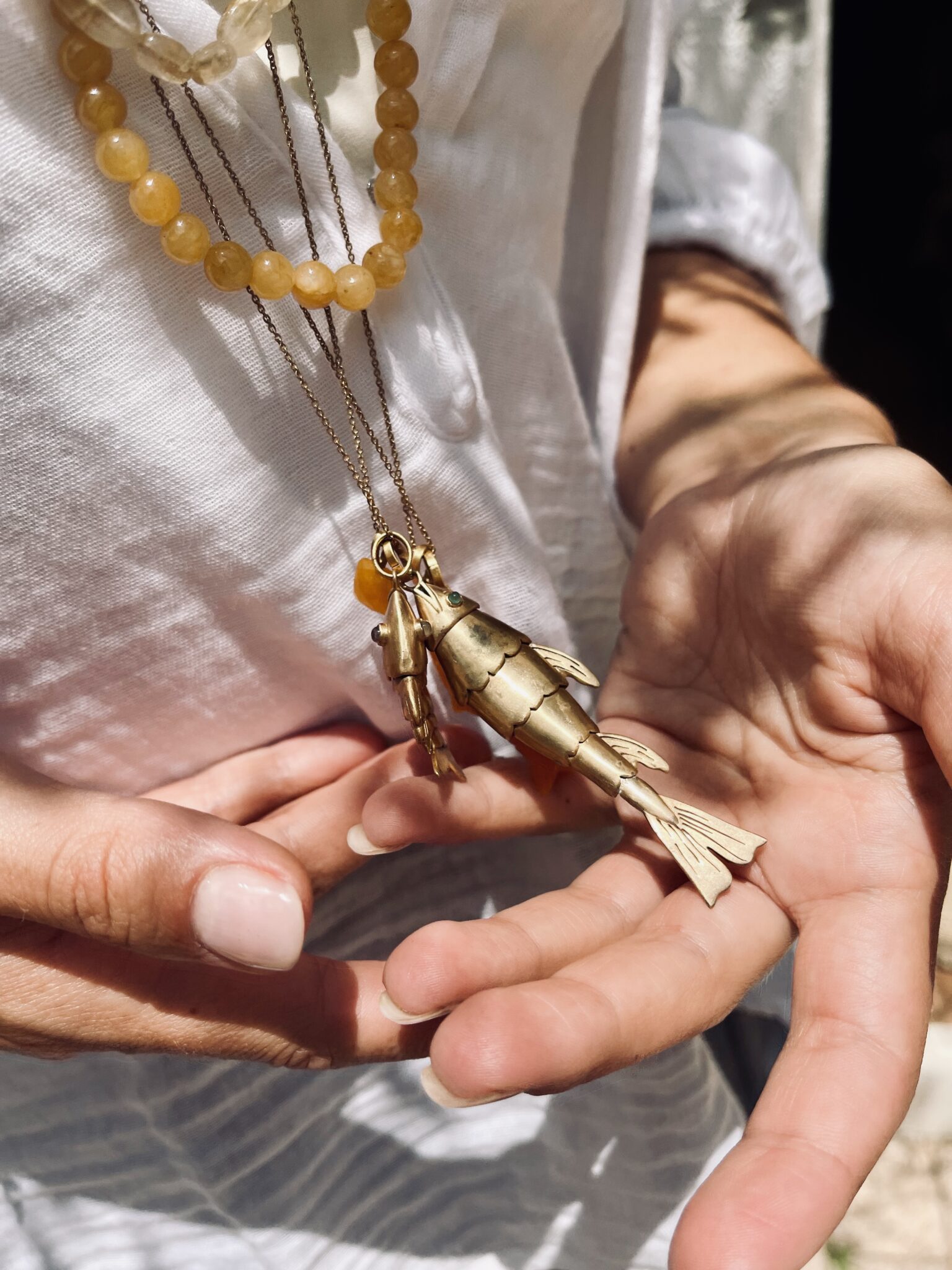 Handmade N°74 jewelry made in India with natural stones, brass details and delicate charms, including the Wave Fish pendant, for Scimparello Magazine.