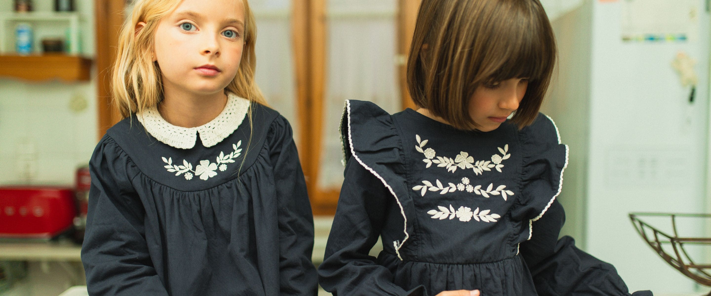 Girls wearing embroidered navy dresses from the C'era Una Volta Fall Winter 2026 children's collection.