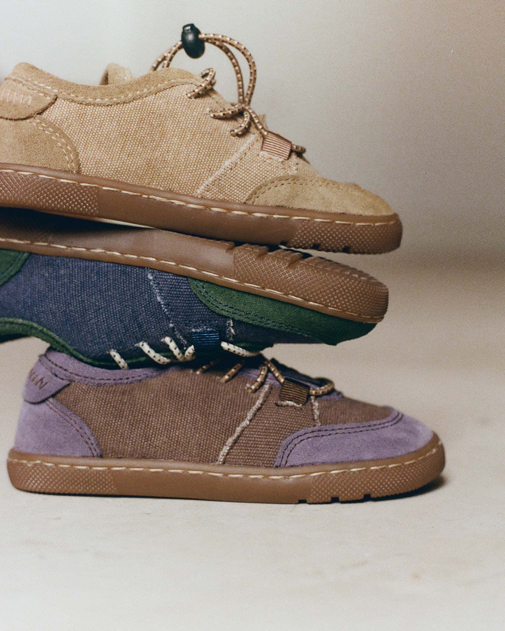 Stack of Maior barefoot sneakers showcasing canvas uppers, suede details and flexible gum soles.