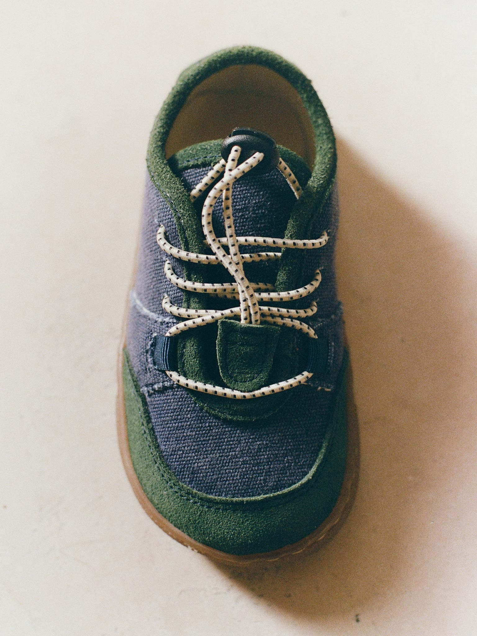Close-up of a navy and green Maior barefoot shoe featuring a wide toe box, elastic laces and flexible sole.