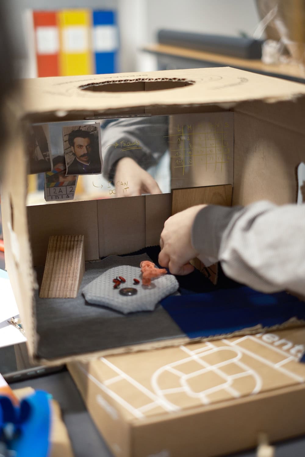 Student testing a cardboard furniture prototype during the Wear & Grow design workshop at Politecnico di Milano, exploring adaptable and emotionally durable solutions for children's interiors.
