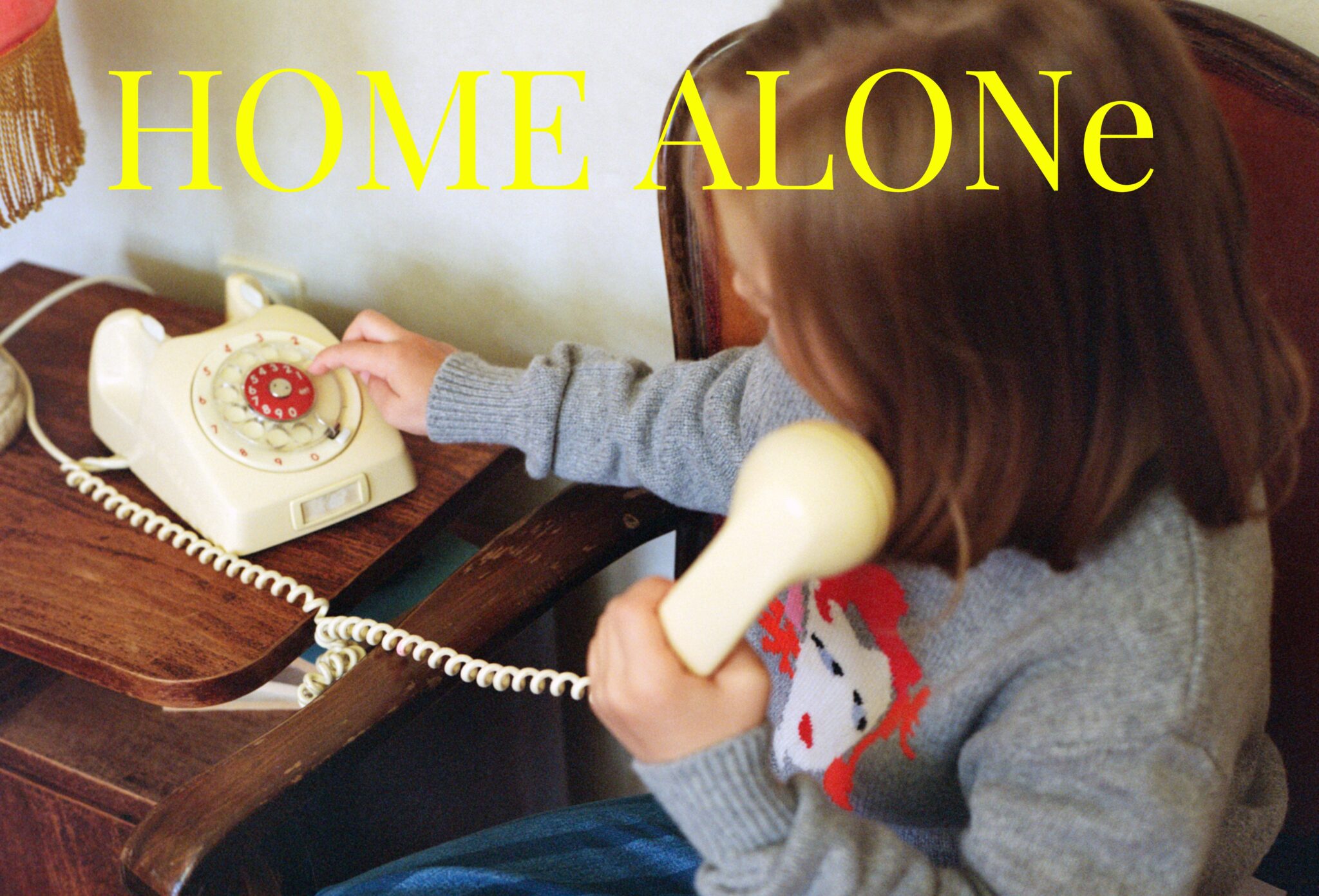 Kids fashion editorial Home Alone photographed and styled by Dasha Chernoglazova, featuring a child playing with a vintage telephone in a cozy home setting with a soft retro feeling for Scimparello Magazine.