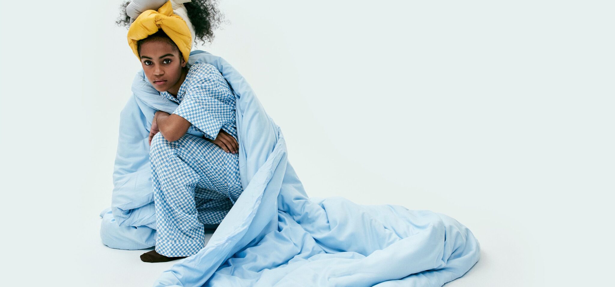 Teen fashion editorial Day Sleepers photographed by Erin Foster and styled by Julie Williams, featuring a girl wrapped in pale blue bedding and wearing blue check pyjamas for Scimparello Magazine.