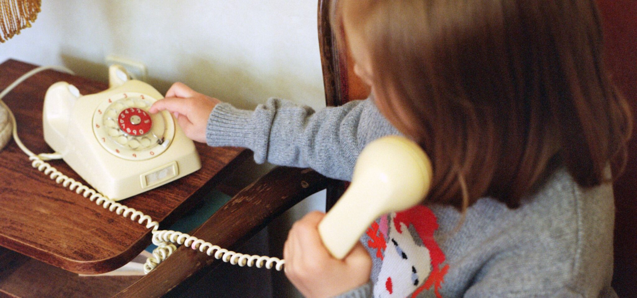 Kids fashion editorial Home Alone photographed and styled by Dasha Chernoglazova, featuring a child playing with a vintage telephone in a cozy home setting with a soft retro feeling for Scimparello Magazine.