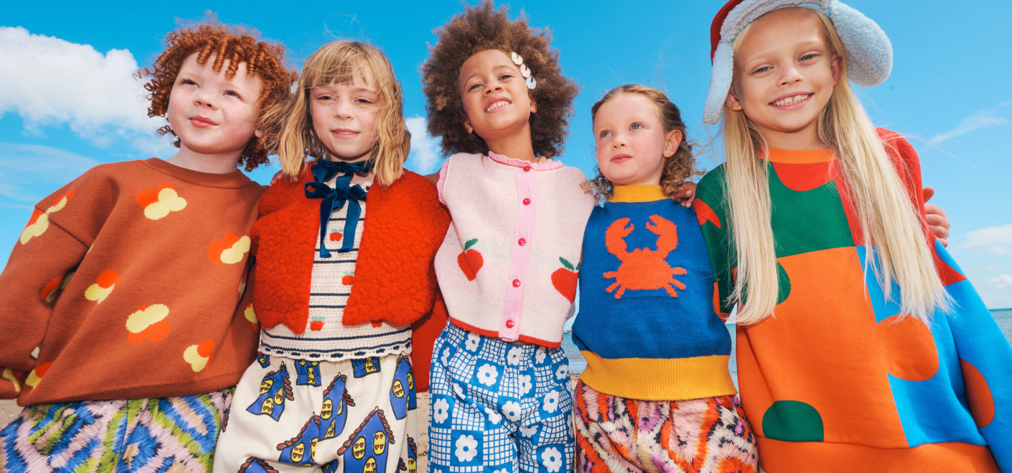 a group of children at the beach in colourful fw26 clothes