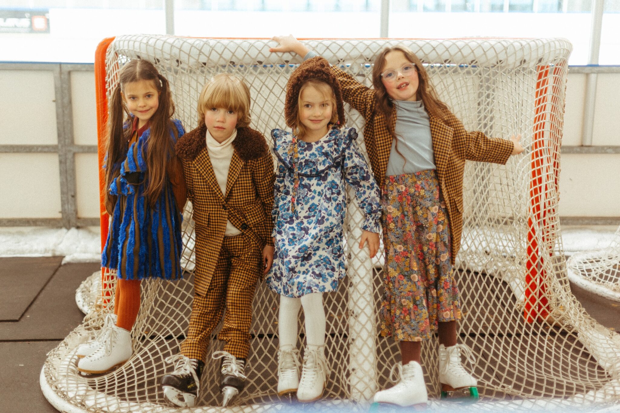 Paade Mode THE STARBOUND FW26 collection, featuring children in artistic winter looks and ice skates posing inside a hockey goal at the rink for Scimparello Magazine.
