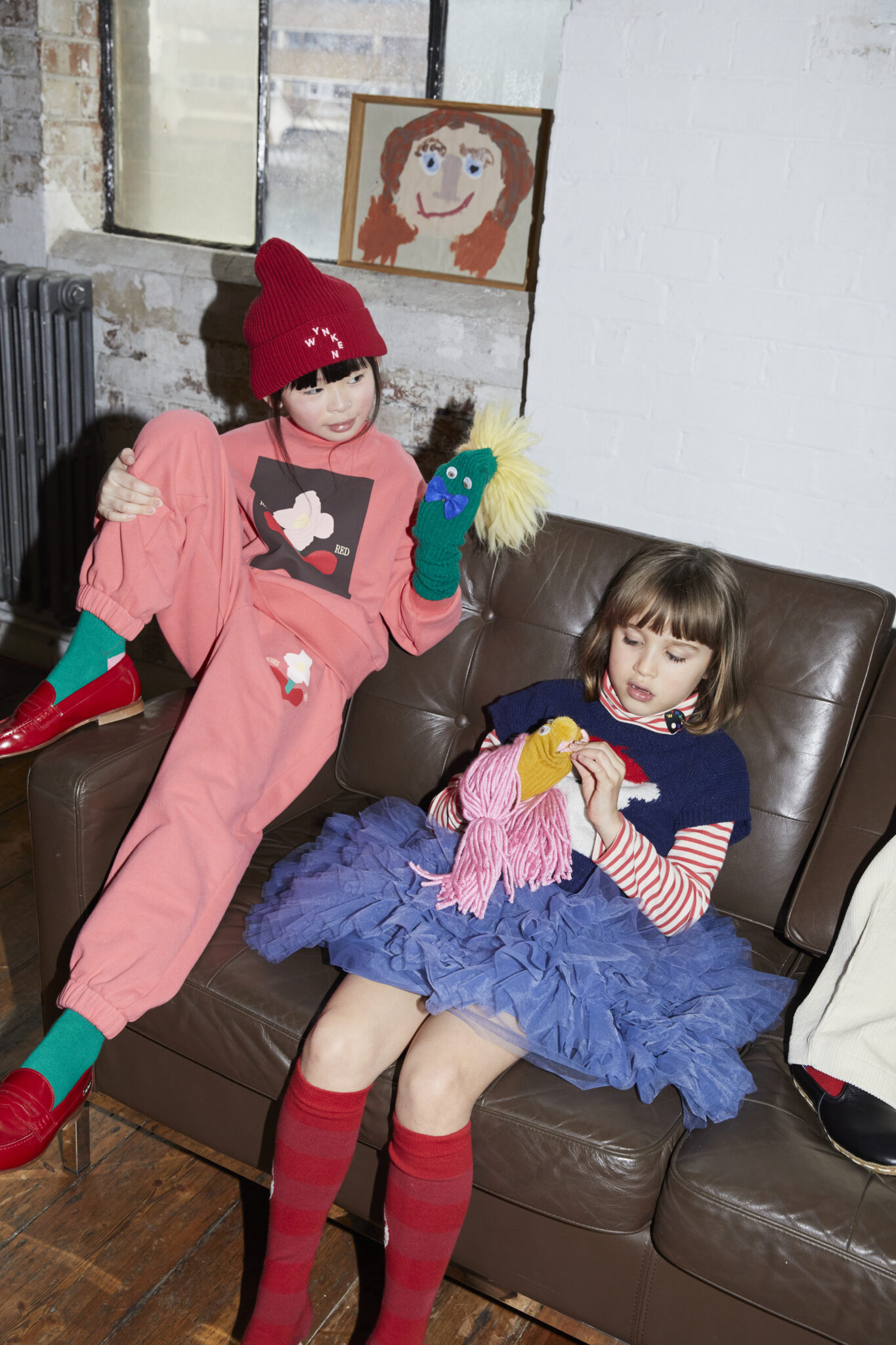 Wynken AW26 collection campaign featuring two children in playful colourful looks, including a pink tracksuit, striped layers and a blue tulle skirt.
