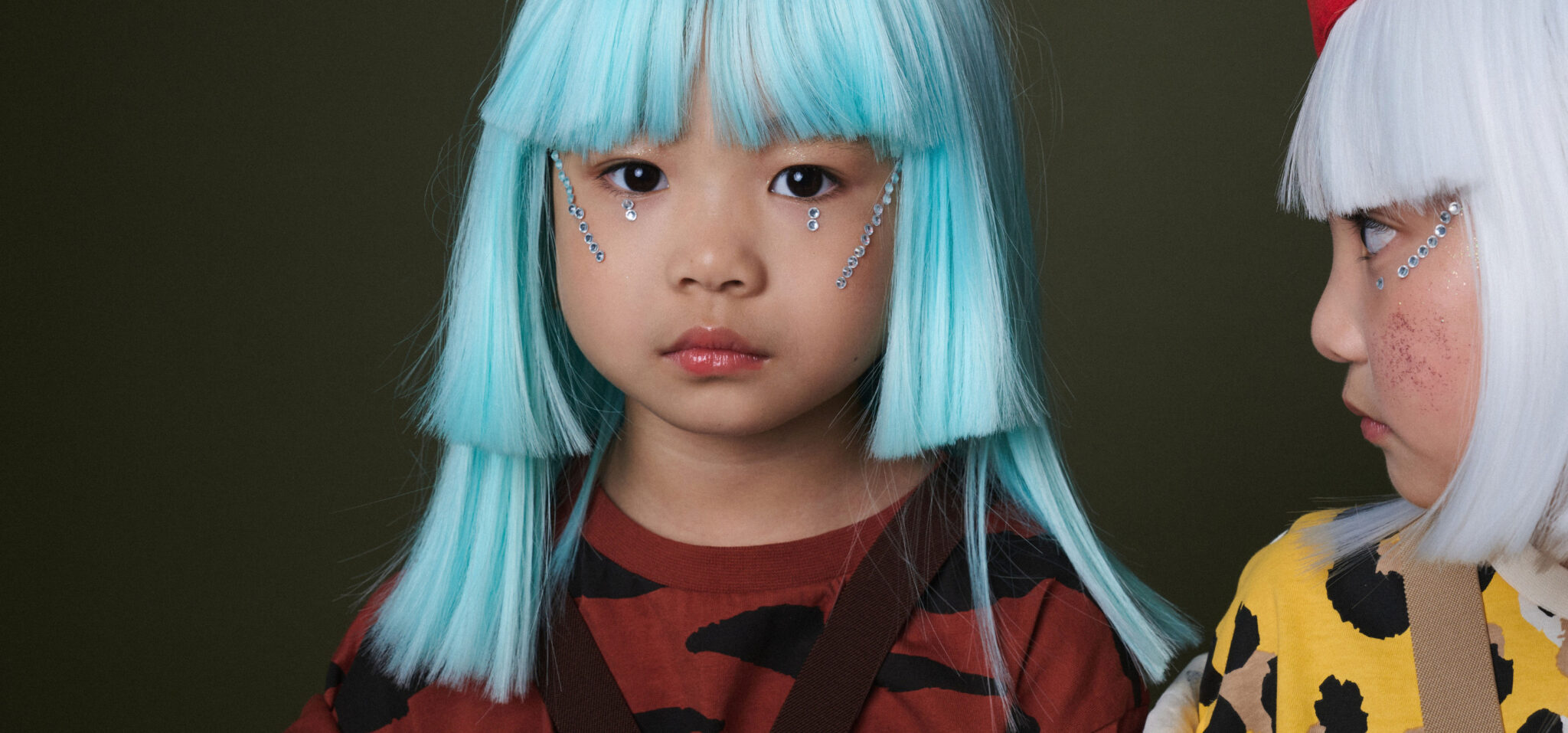 Two girls in white and turquoise wigs, leopard and tiger print T-shirts