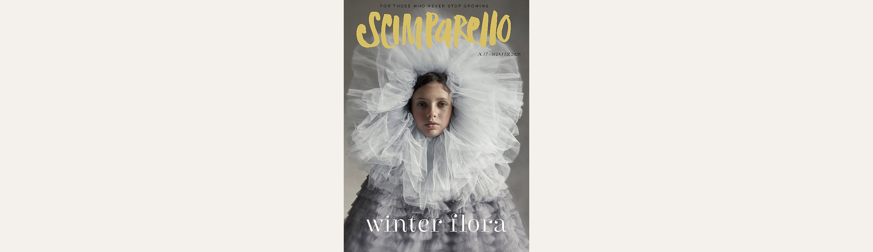 Cover of Scimparello N°17 Winter 2026, Winter Flora: a child wrapped in a huge cloud of pale grey tulle, with the yellow Scimparello logo above and 