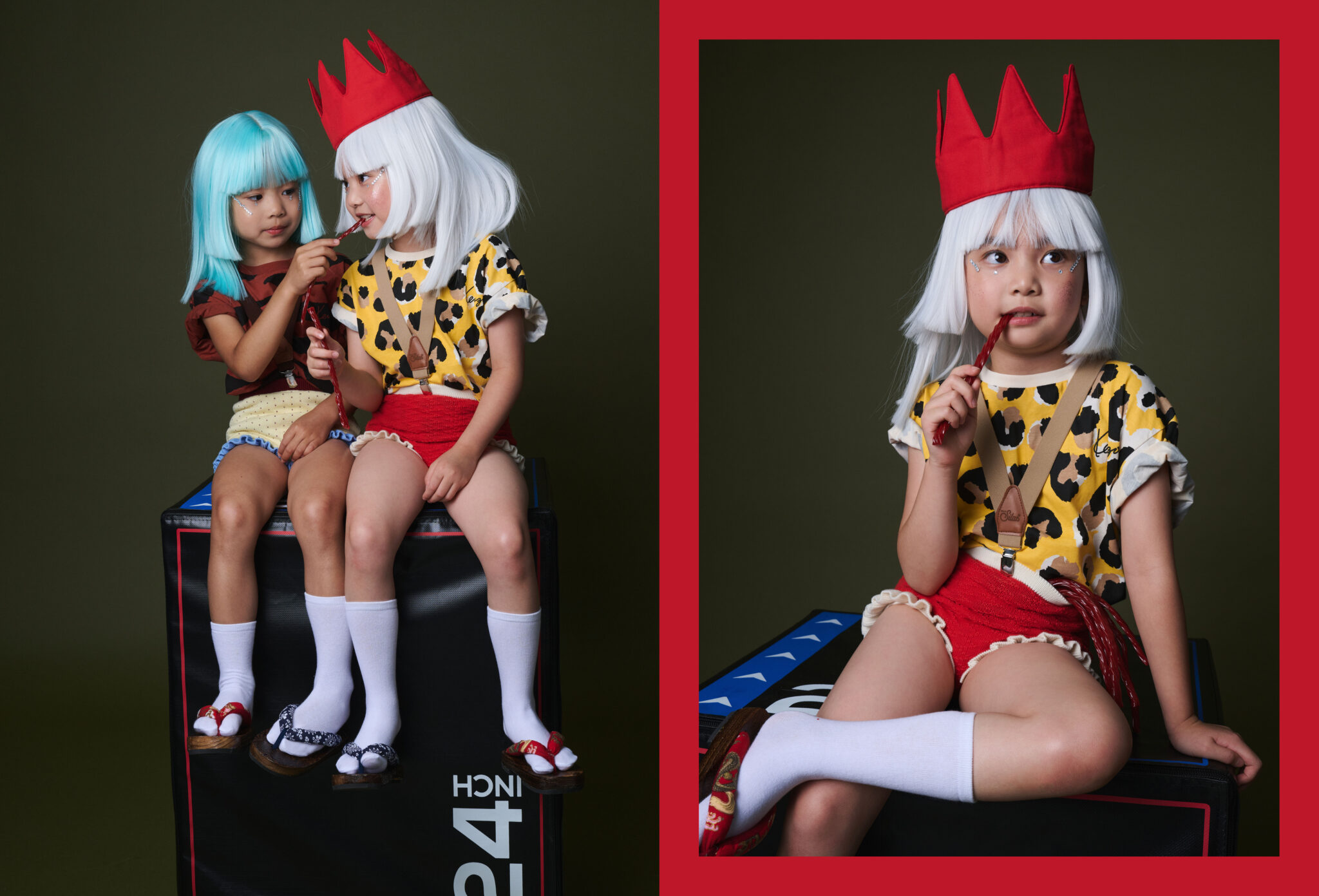 Two girls in wigs sharing red liquorice on a plyo box, and a girl in a red crown biting a liquorice stick