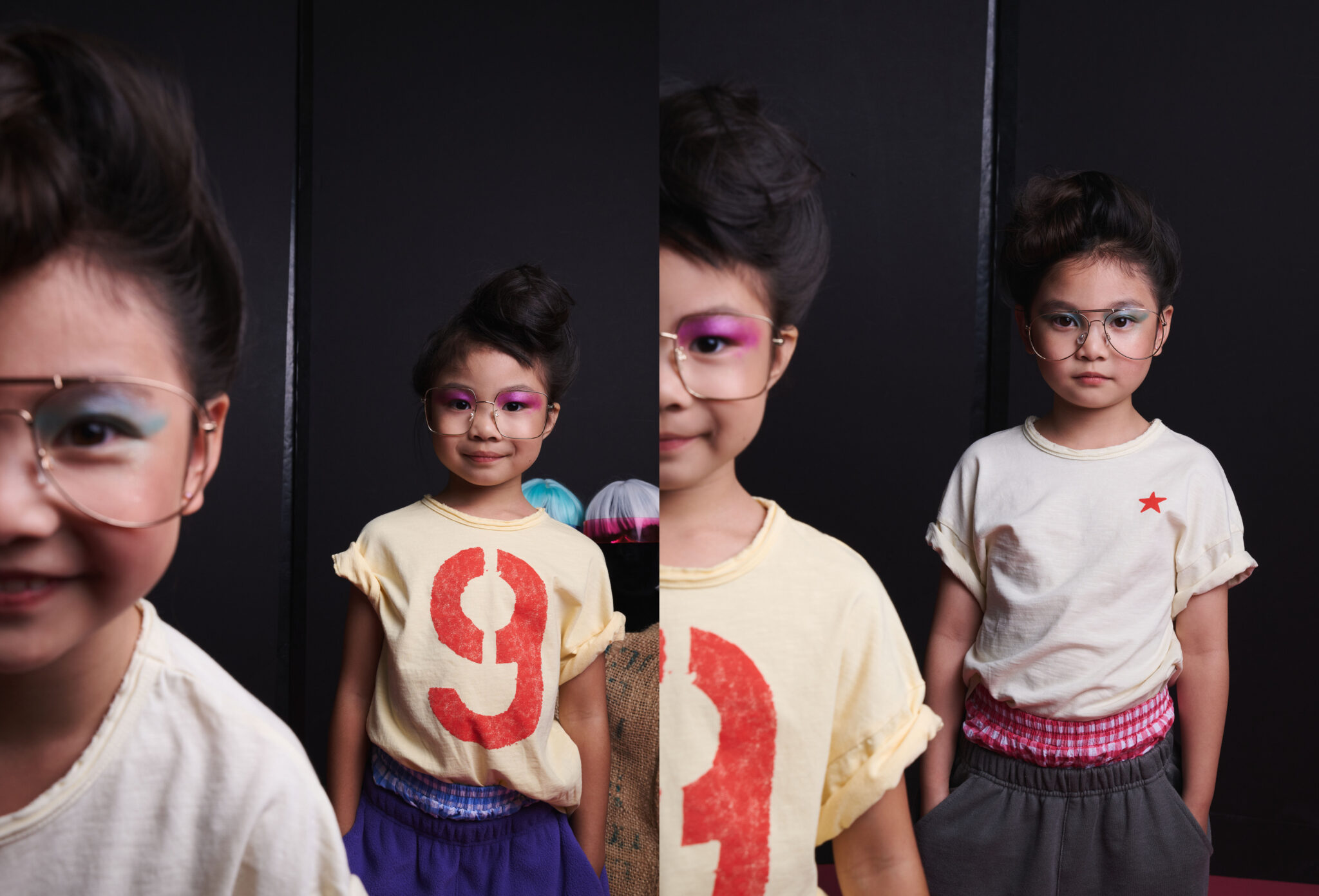 Two girls in glasses and colourful eye make-up wearing yellow T-shirts, one printed with a red number 9 and one with a red star