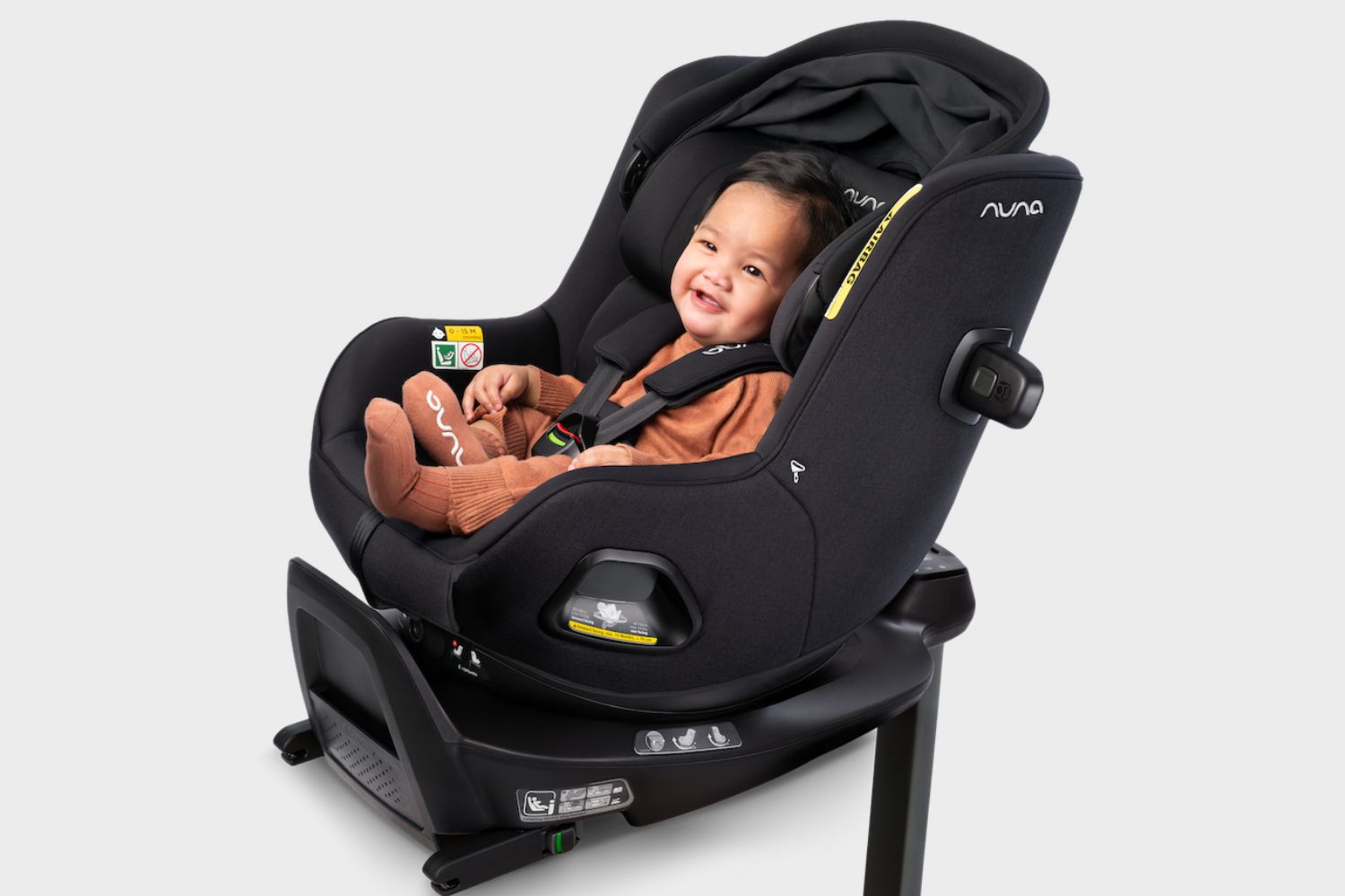 Nuna RELX wind rotating car seat with a child seated comfortably in the black car seat, featuring a protective sun canopy and adjustable five-point harness.